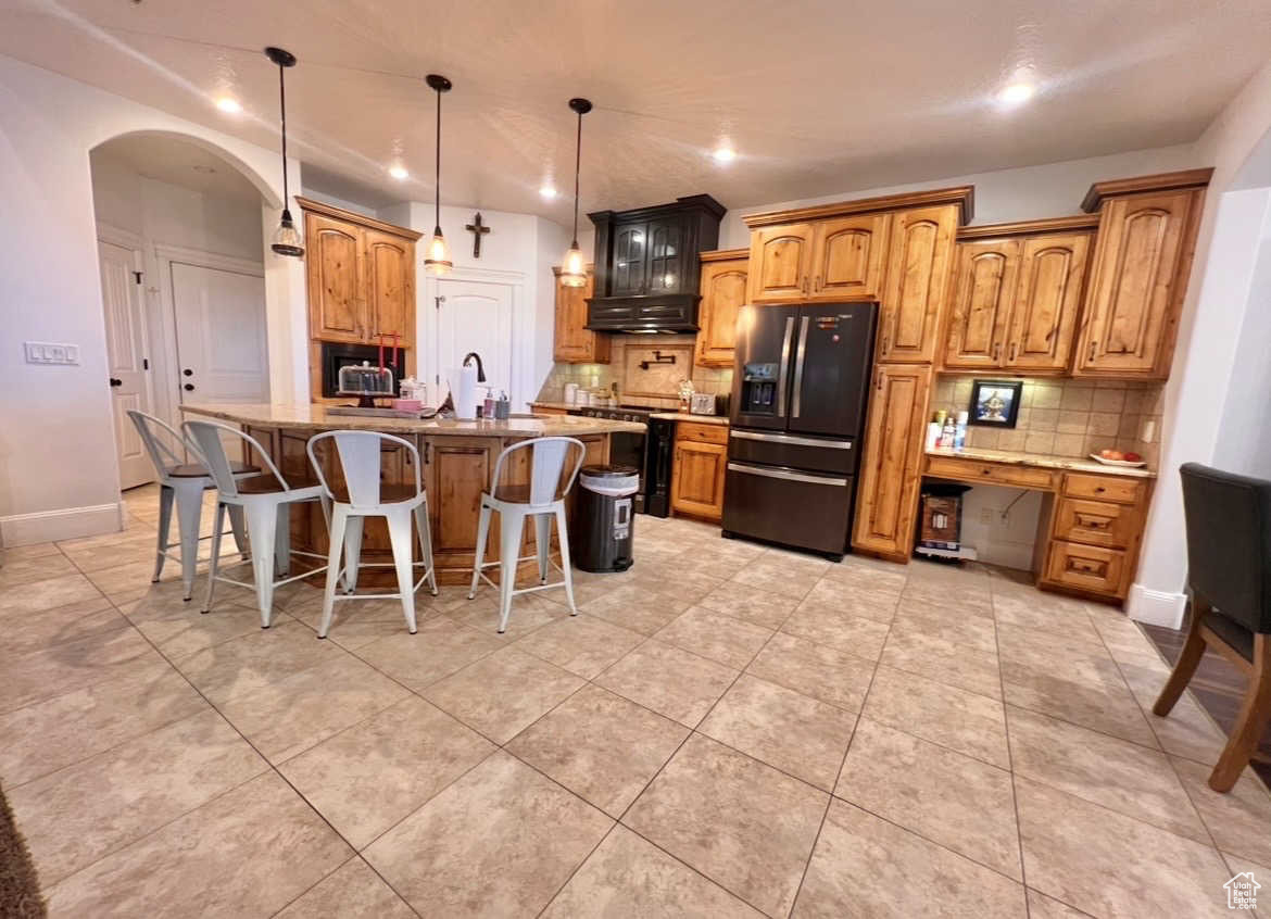 Kitchen featuring hanging light fixtures, a breakfast bar area, black appliances, and a center island