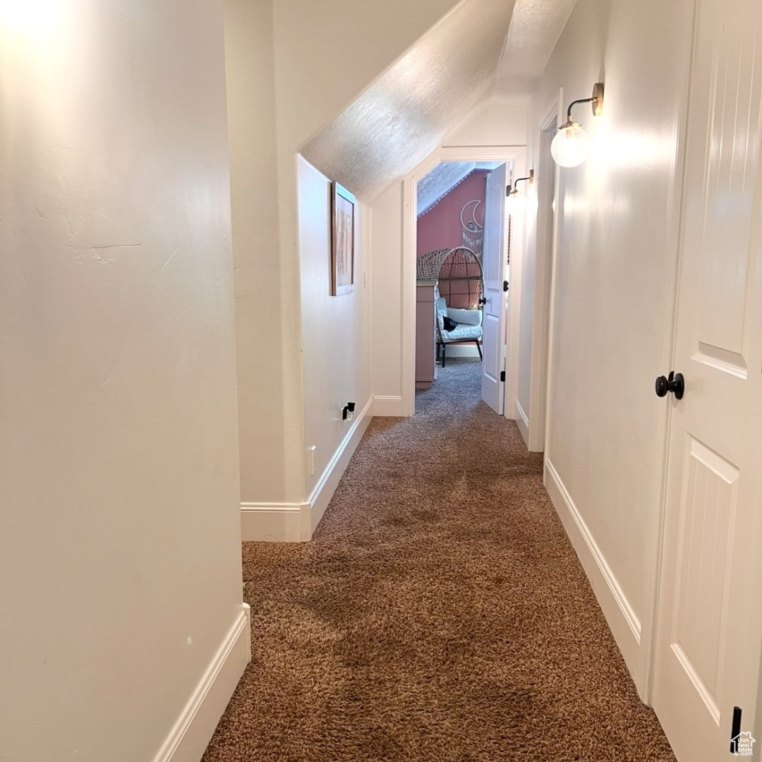 Hallway featuring lofted ceiling and carpet floors