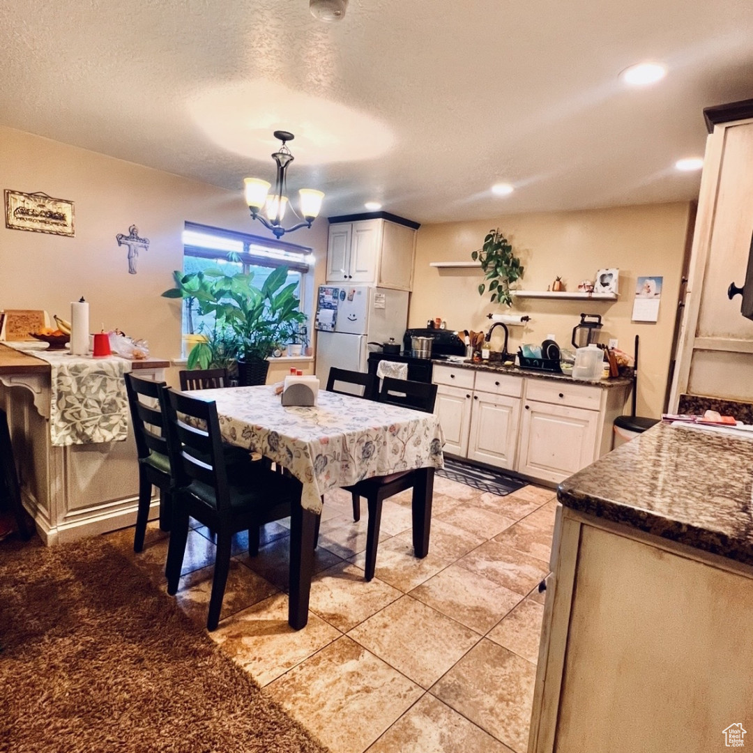 Dining space with light tile patterned flooring, a chandelier, and a textured ceiling