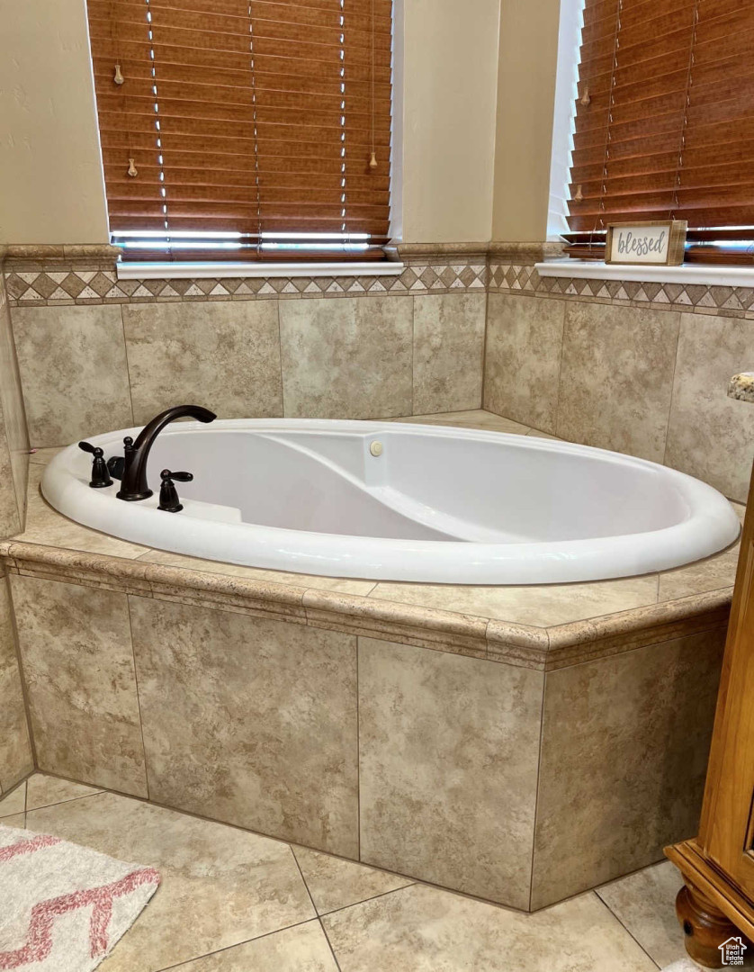 Bathroom with tiled tub and tile patterned floors