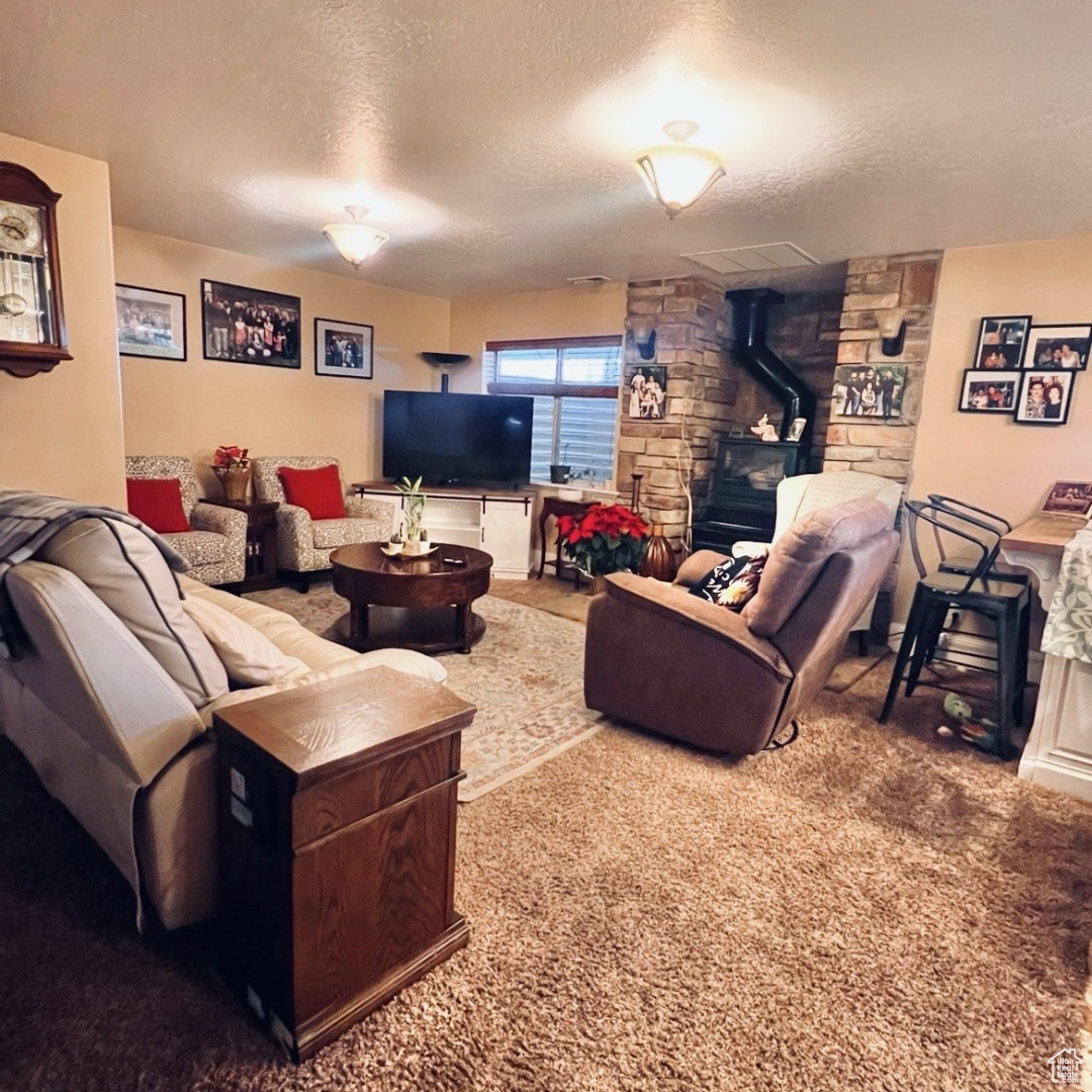 Living room featuring carpet floors, a wood stove, and a textured ceiling