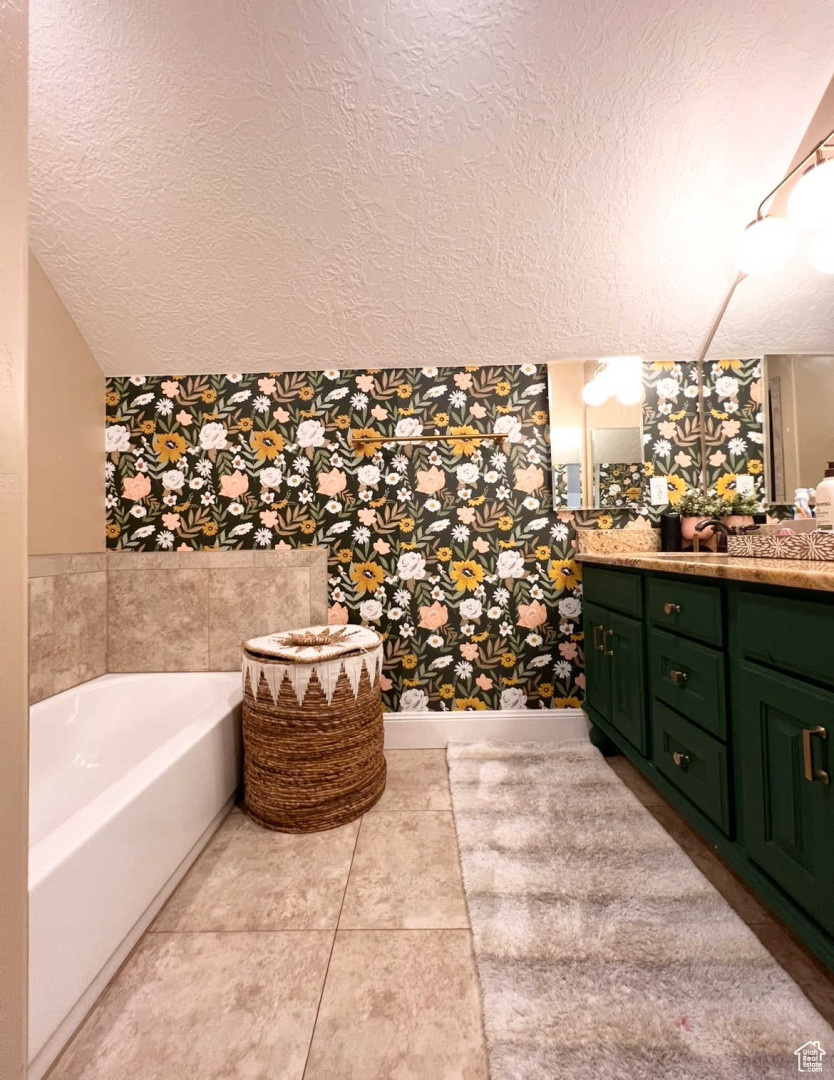 Bathroom with vanity, a bath, tile patterned floors, and a textured ceiling