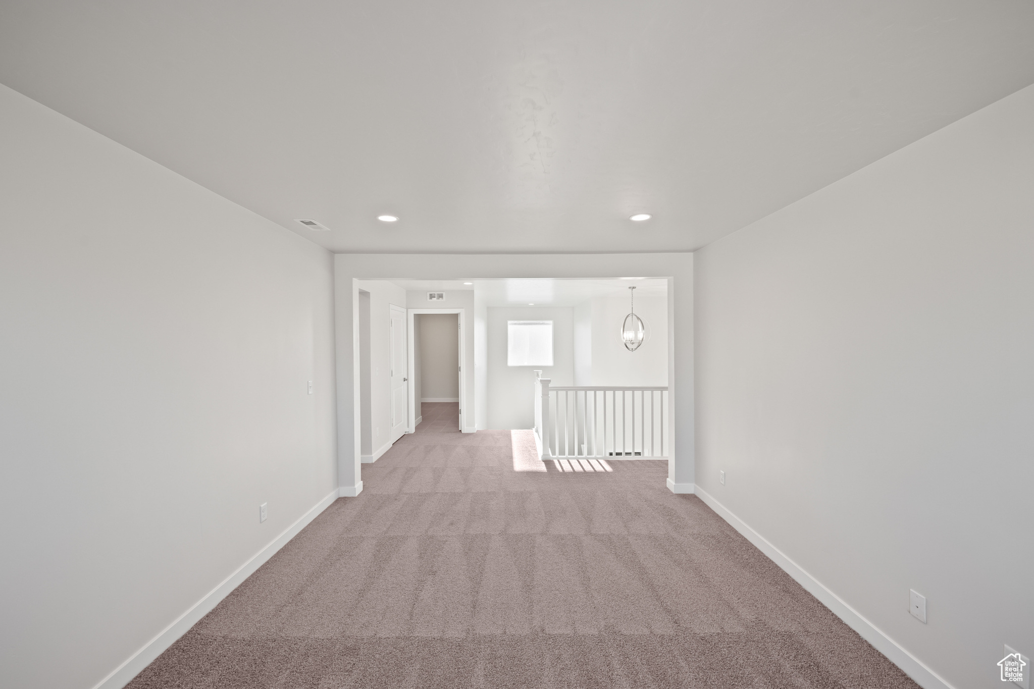 Carpeted spare room featuring a chandelier