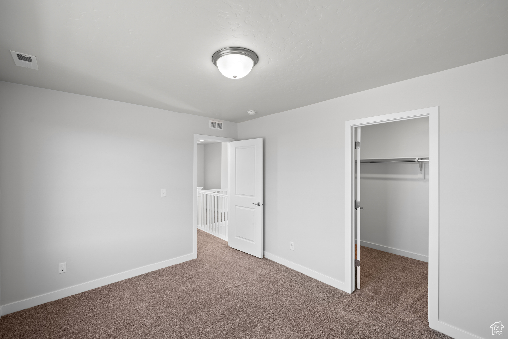 Unfurnished bedroom featuring a walk in closet, a closet, and carpet