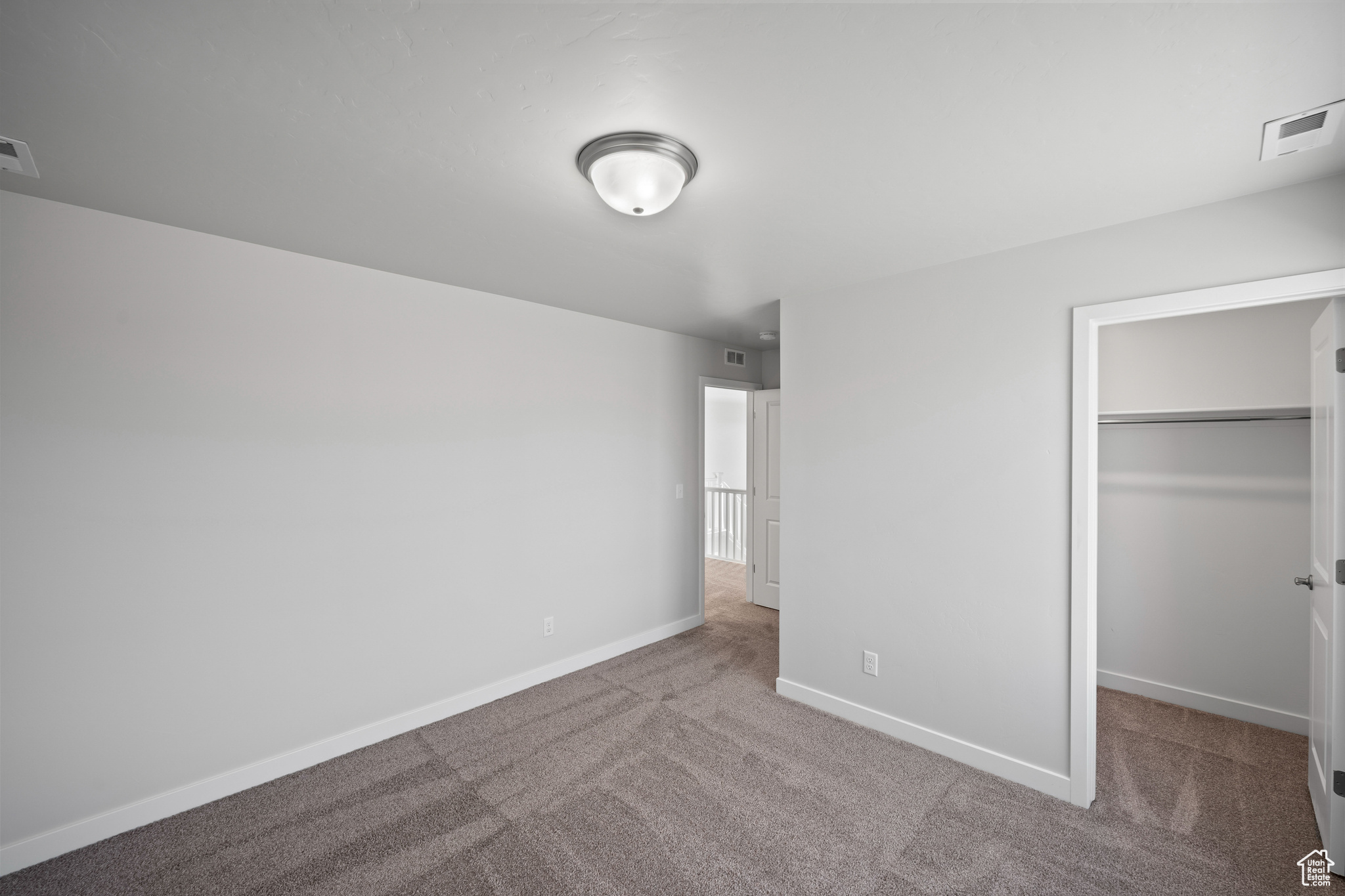 Unfurnished bedroom featuring a walk in closet, a closet, and carpet