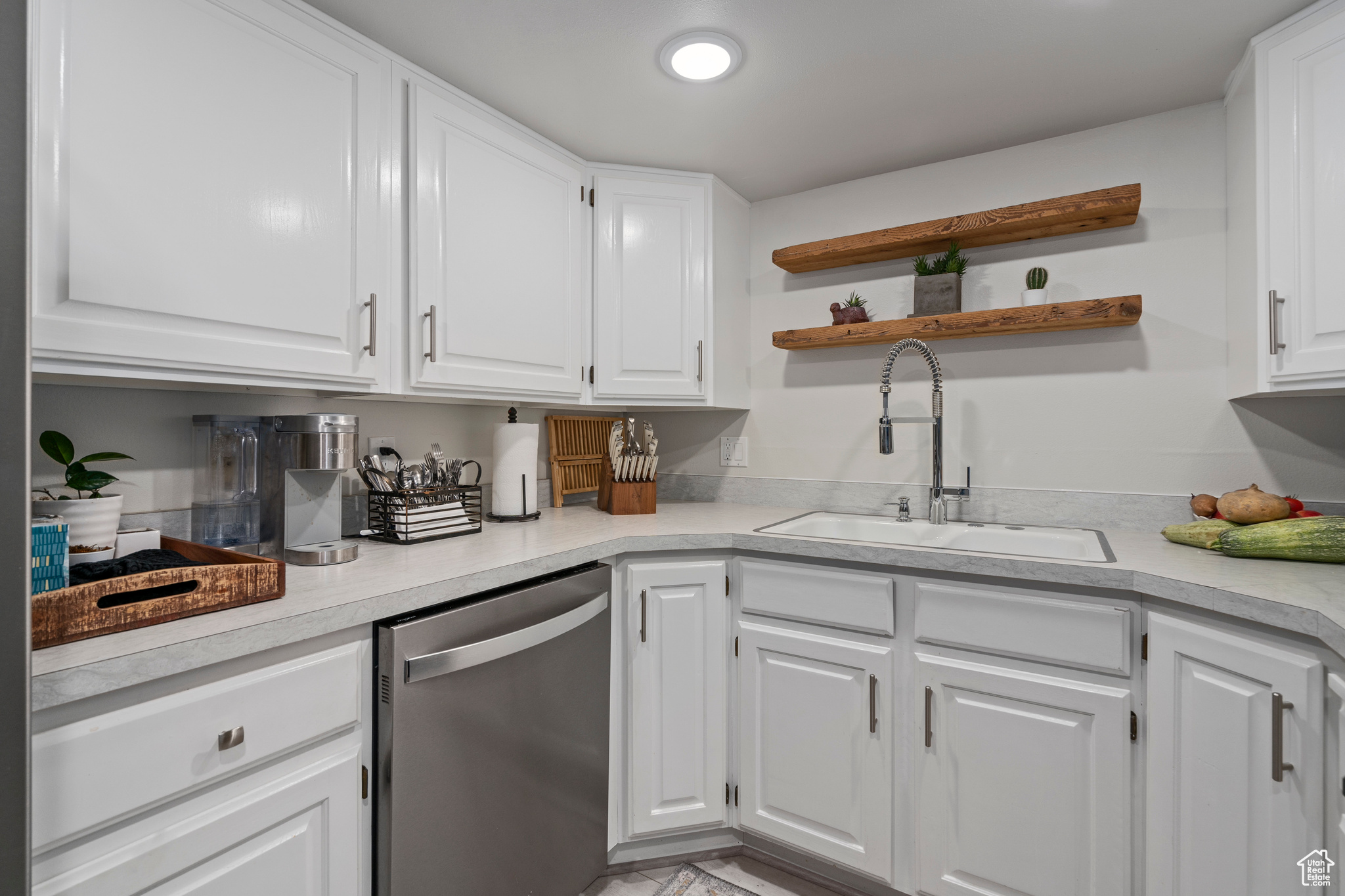 Kitchen featuring sink, stainless steel dishwasher, and white cabinets