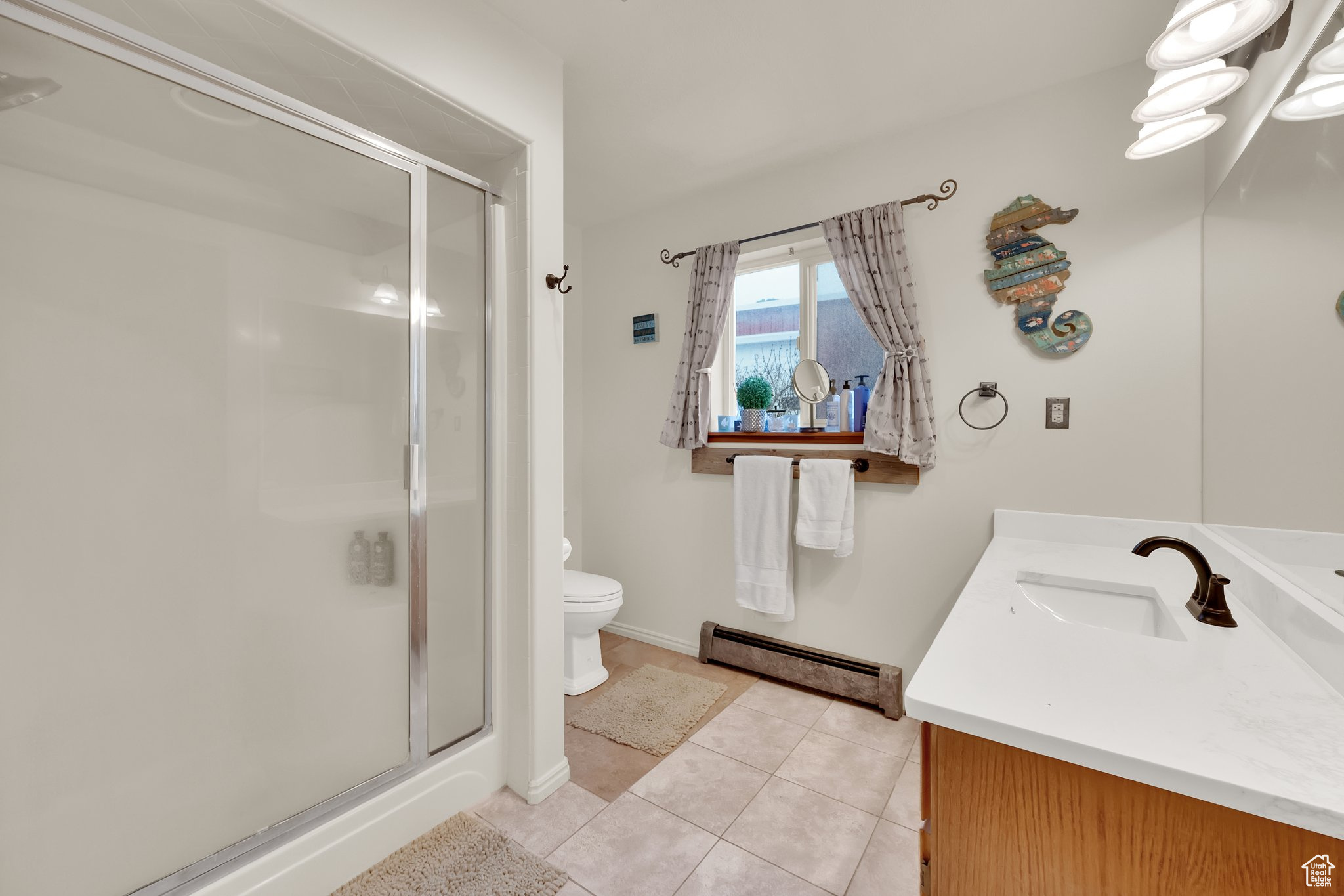 Bathroom featuring tile patterned floors, toilet, a baseboard radiator, vanity, and a shower with door