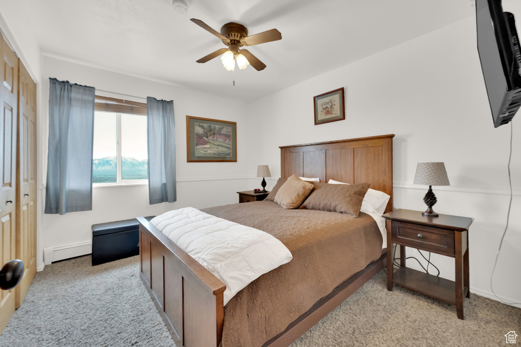 Bedroom featuring ceiling fan, light colored carpet, and a baseboard heating unit