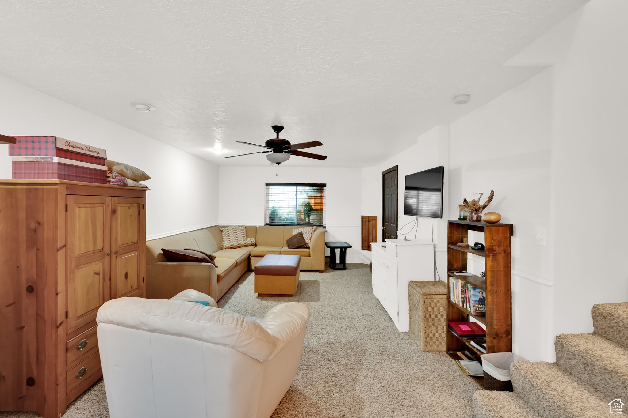 Living room featuring light carpet, a textured ceiling, and ceiling fan