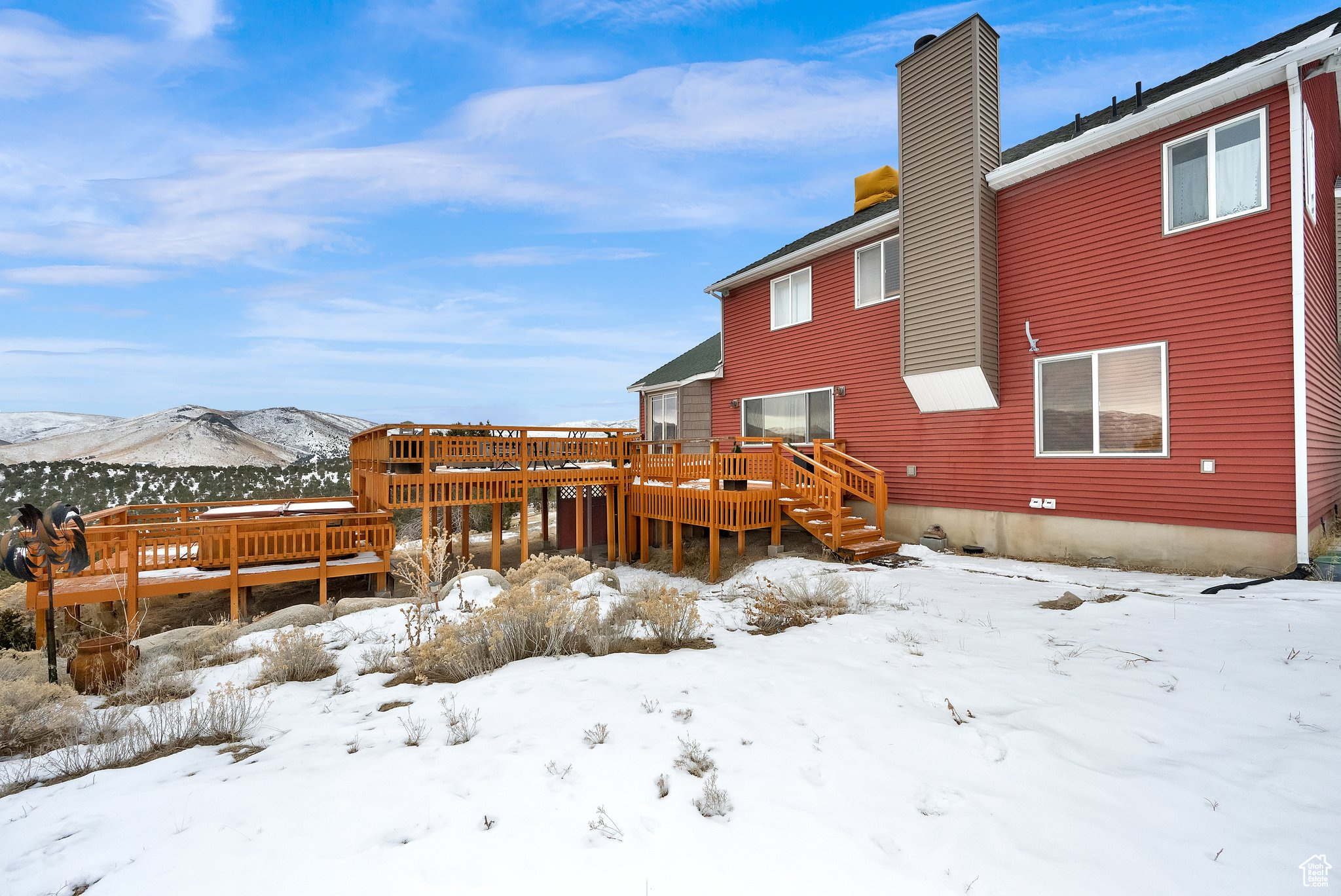 Snow covered house featuring a deck with mountain view