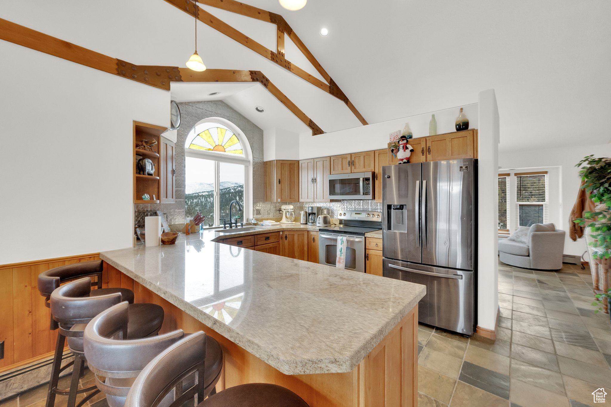 Kitchen featuring appliances with stainless steel finishes, decorative light fixtures, sink, a breakfast bar area, and kitchen peninsula