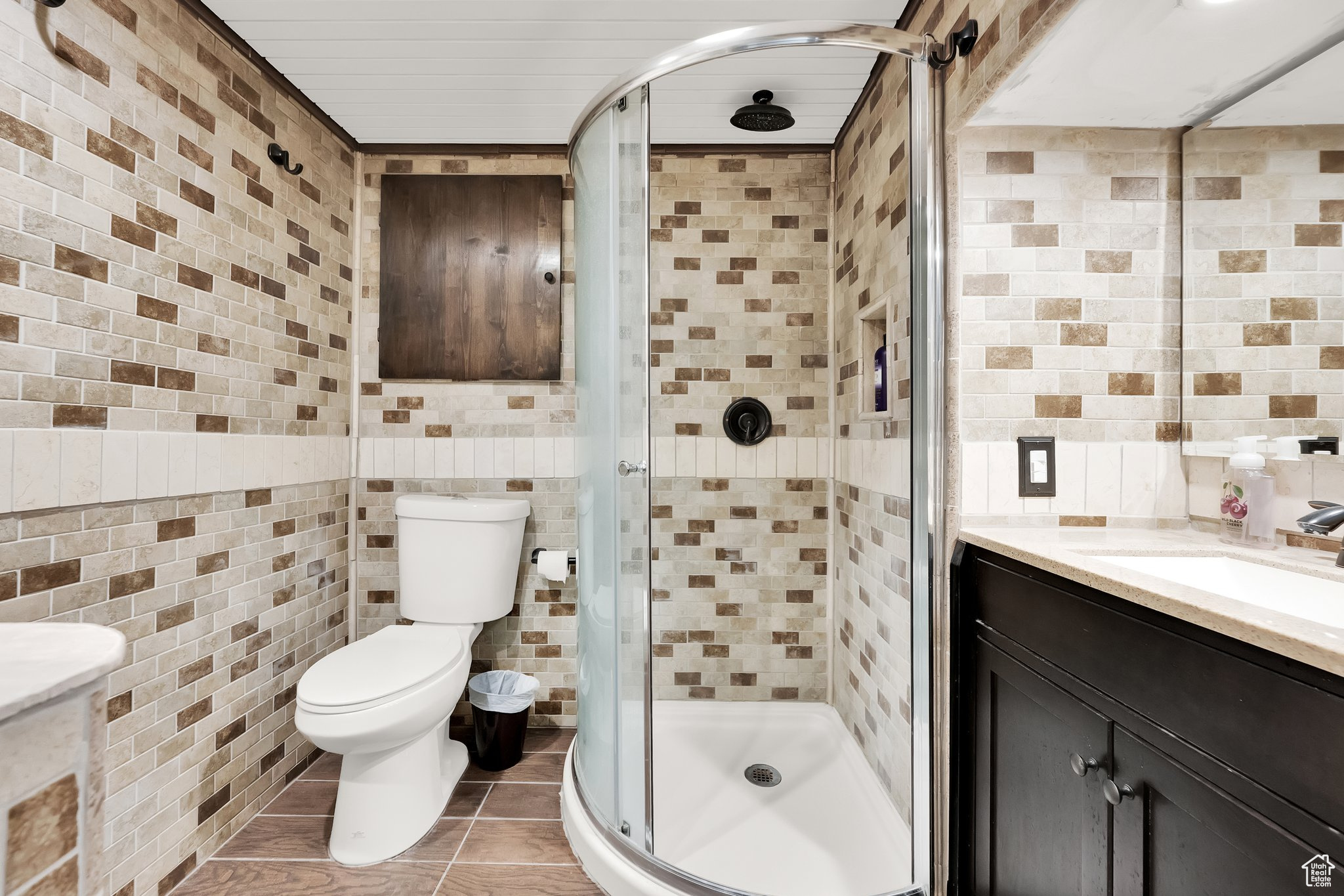 Bathroom with vanity, tile walls, tile patterned floors, and a shower with shower door