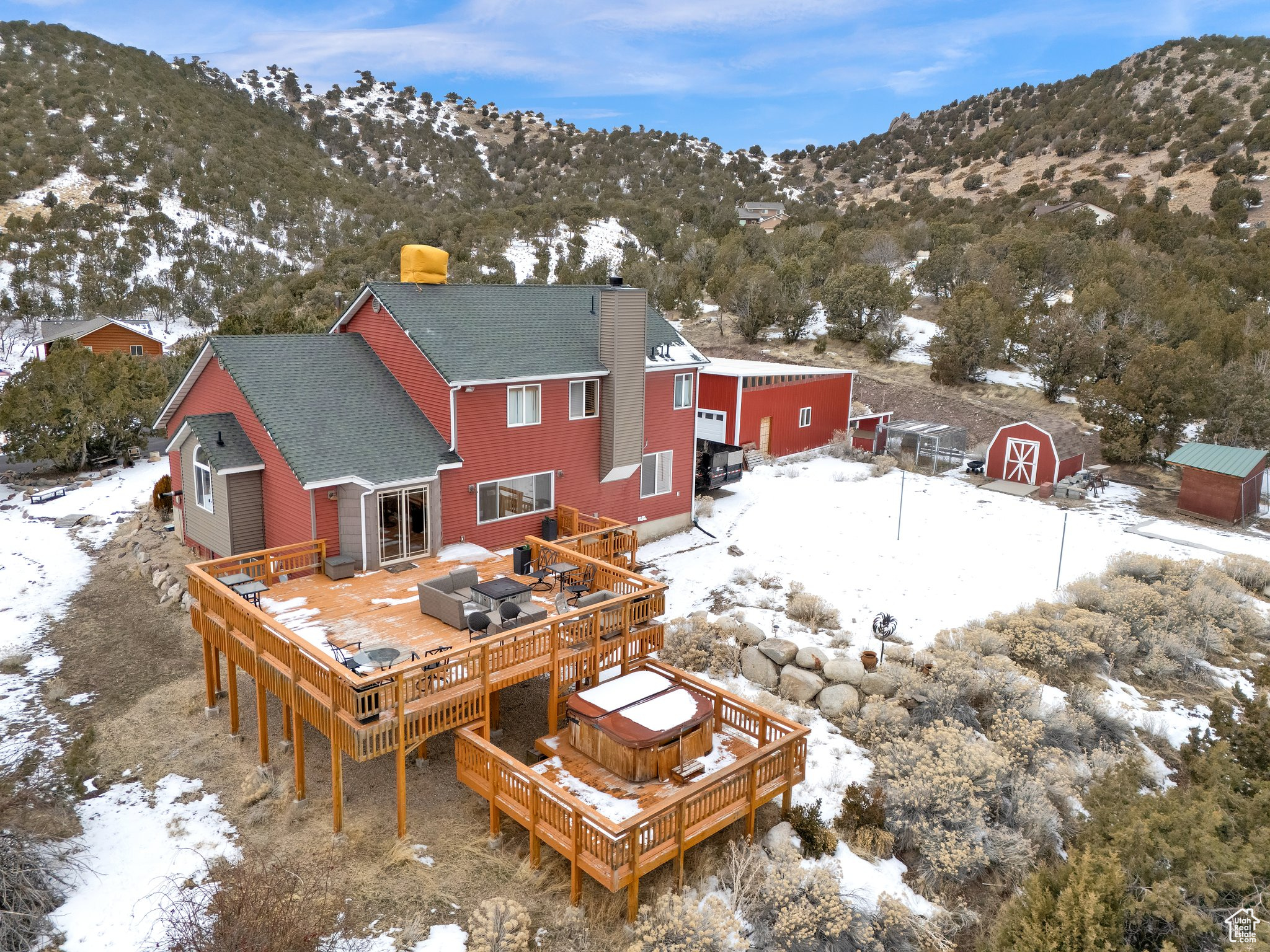 Snow covered property featuring a storage unit, a hot tub, and a deck with mountain view