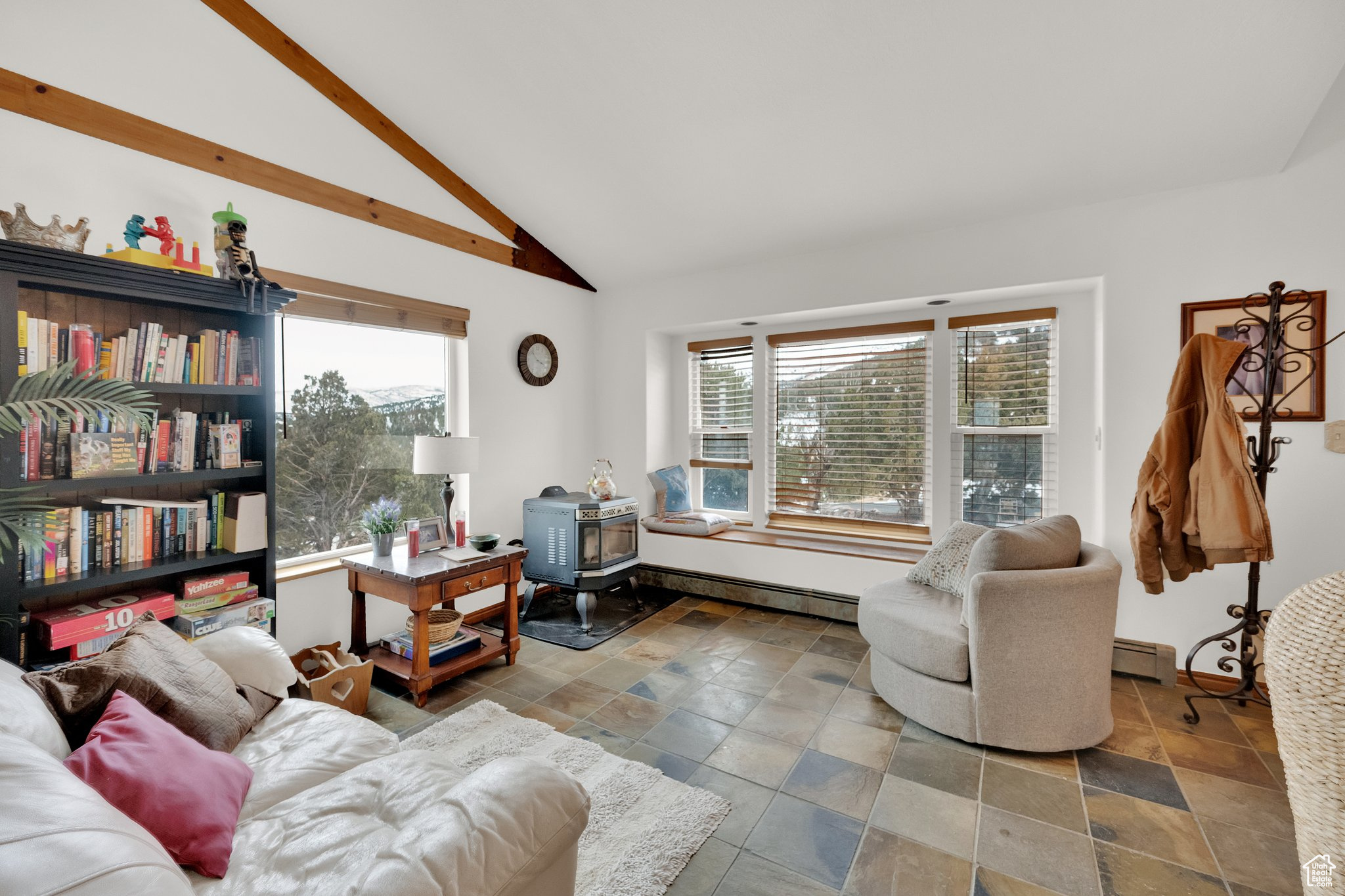 Living room featuring a baseboard heating unit, high vaulted ceiling, and a wood stove