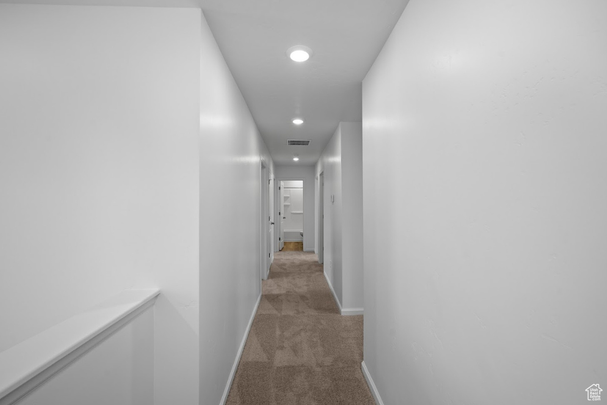 Hallway leading to 4 bedrooms and laundry with light carpet