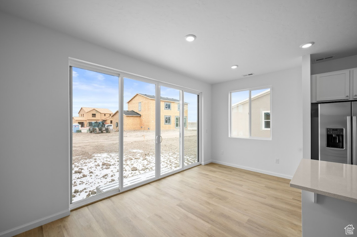 Unfurnished dining area featuring light LVT wood-style flooring and double wide sliding doors