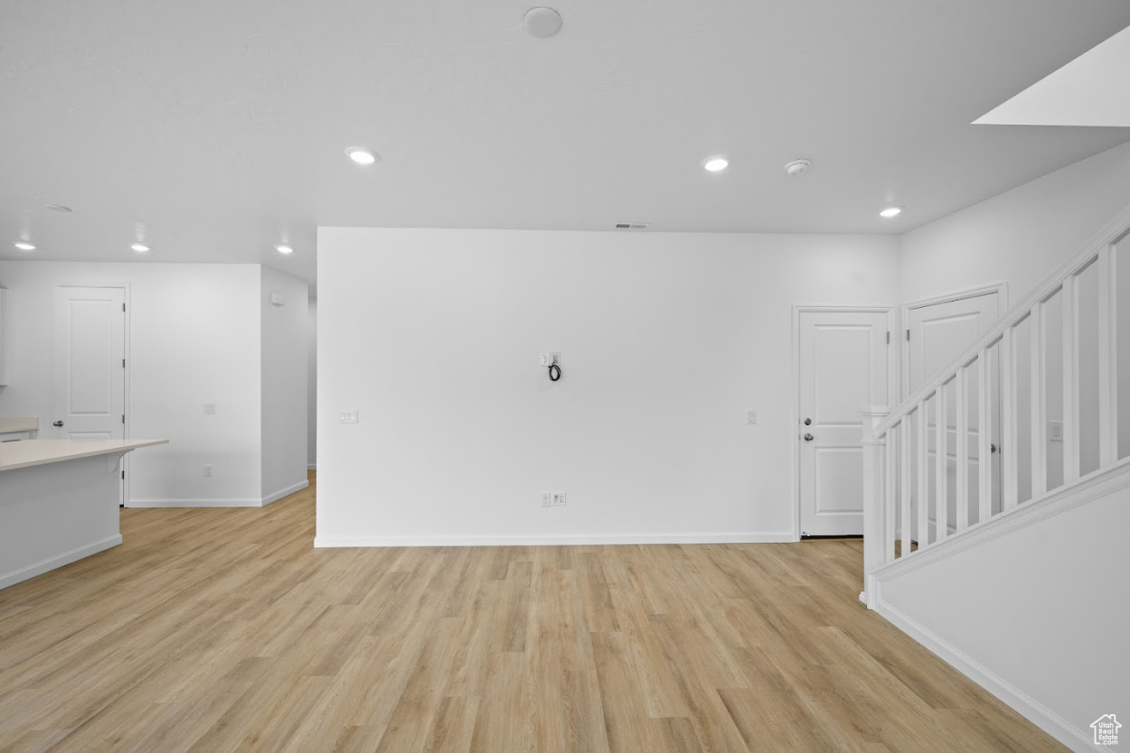 Unfurnished living room with cables for TV and open railing on stairs.