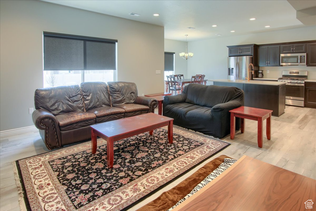 Living room with sink, an inviting chandelier, and light hardwood / wood-style floors