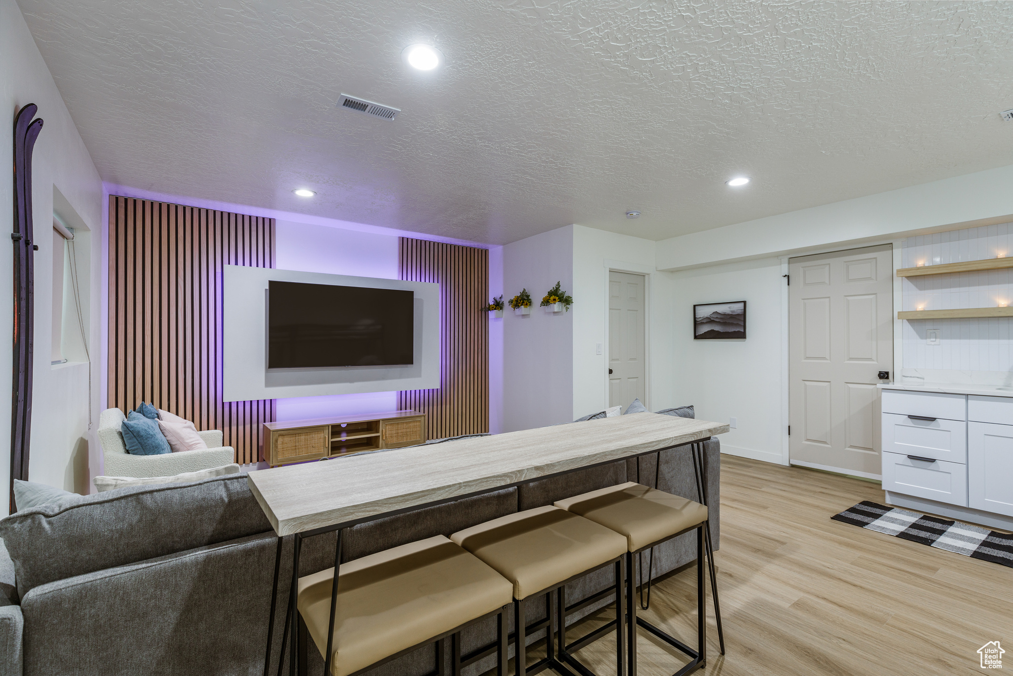 Cinema room with light hardwood / wood-style floors and a textured ceiling