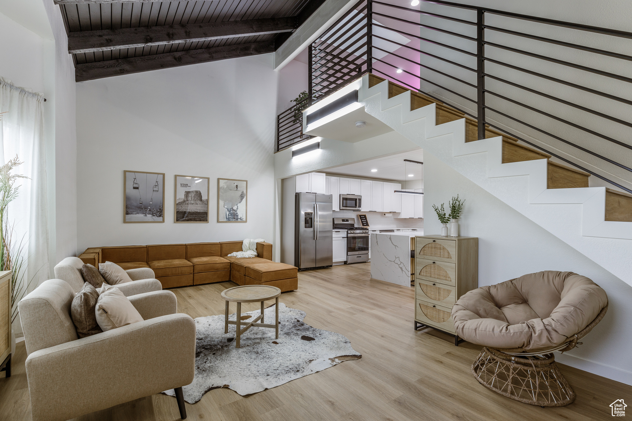 Living room featuring beamed ceiling, wooden ceiling, a high ceiling, and light wood-type flooring