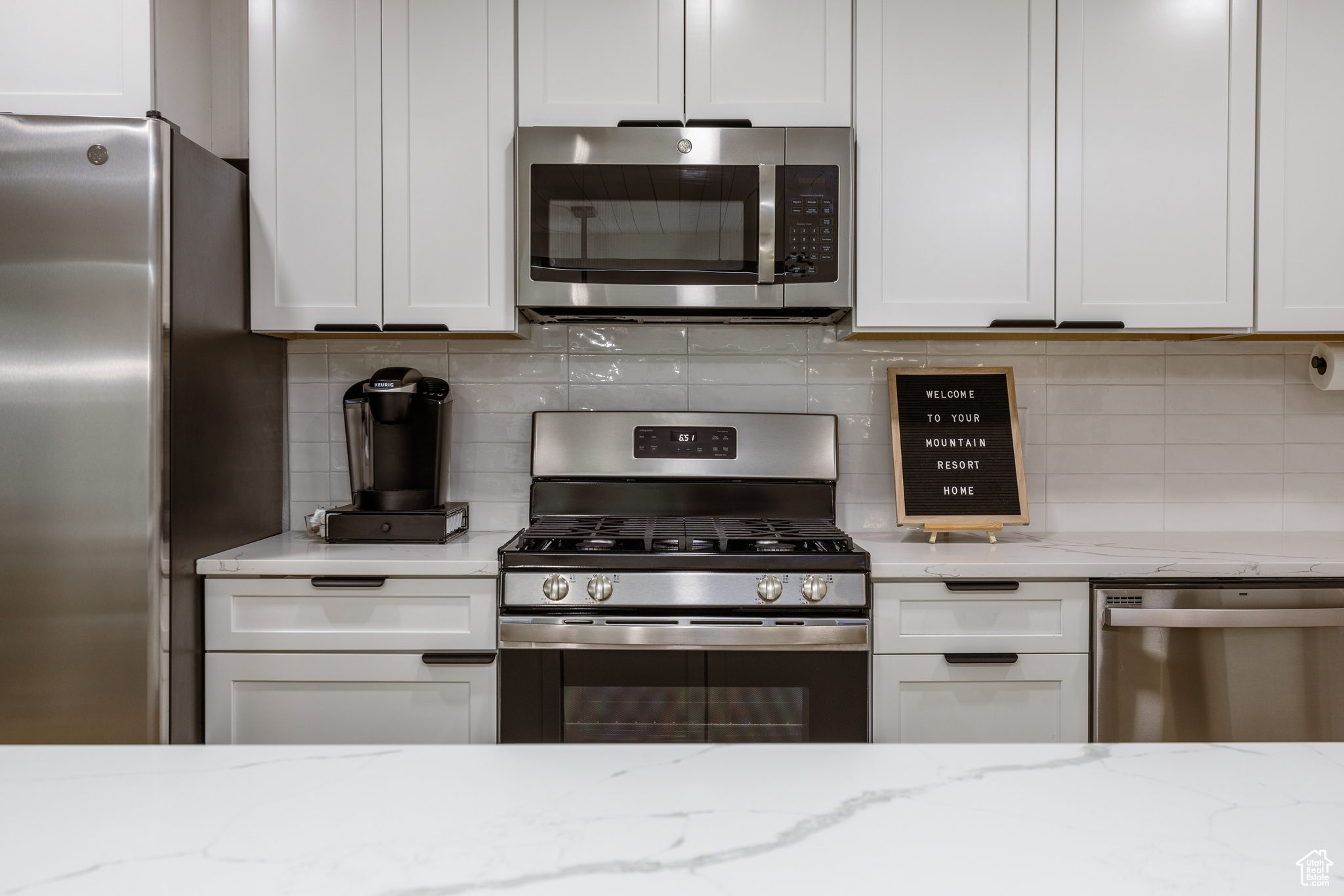 Kitchen featuring white cabinetry, stainless steel appliances, and light stone countertops