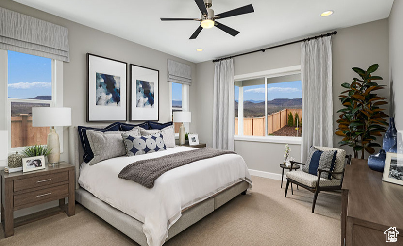 Bedroom with ceiling fan, light colored carpet, and multiple windows