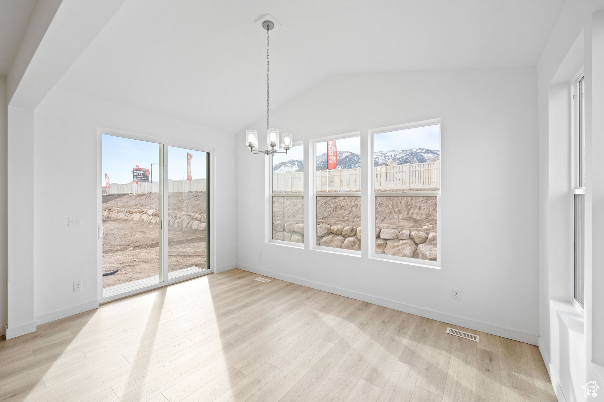 Unfurnished dining area featuring a mountain view, lofted ceiling, light wood-type flooring, and a notable chandelier