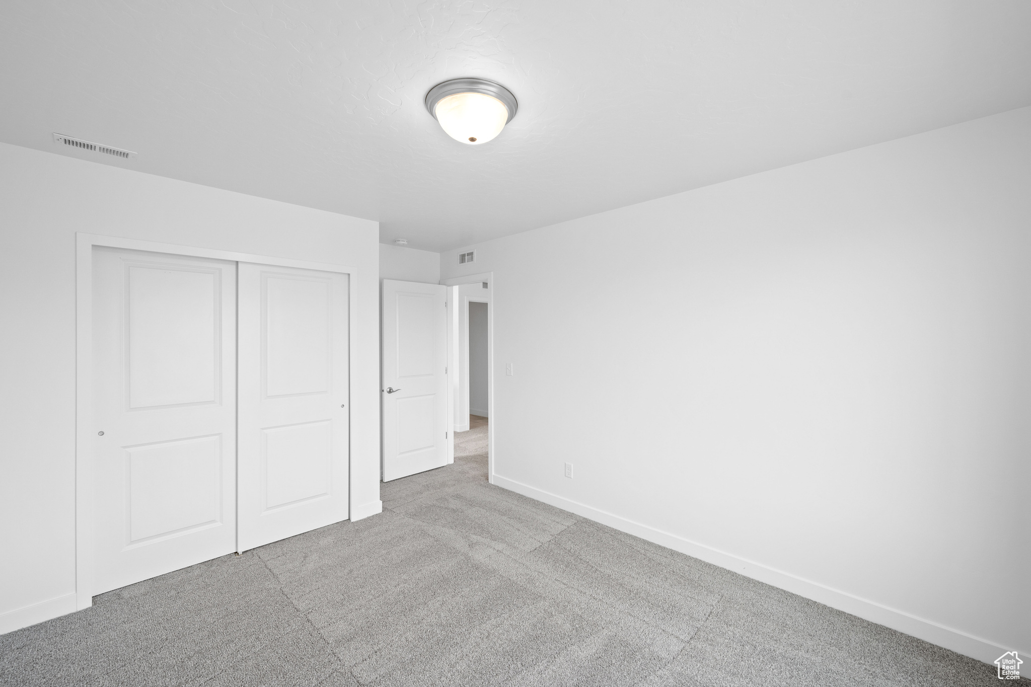 Unfurnished bedroom featuring light carpet and a closet