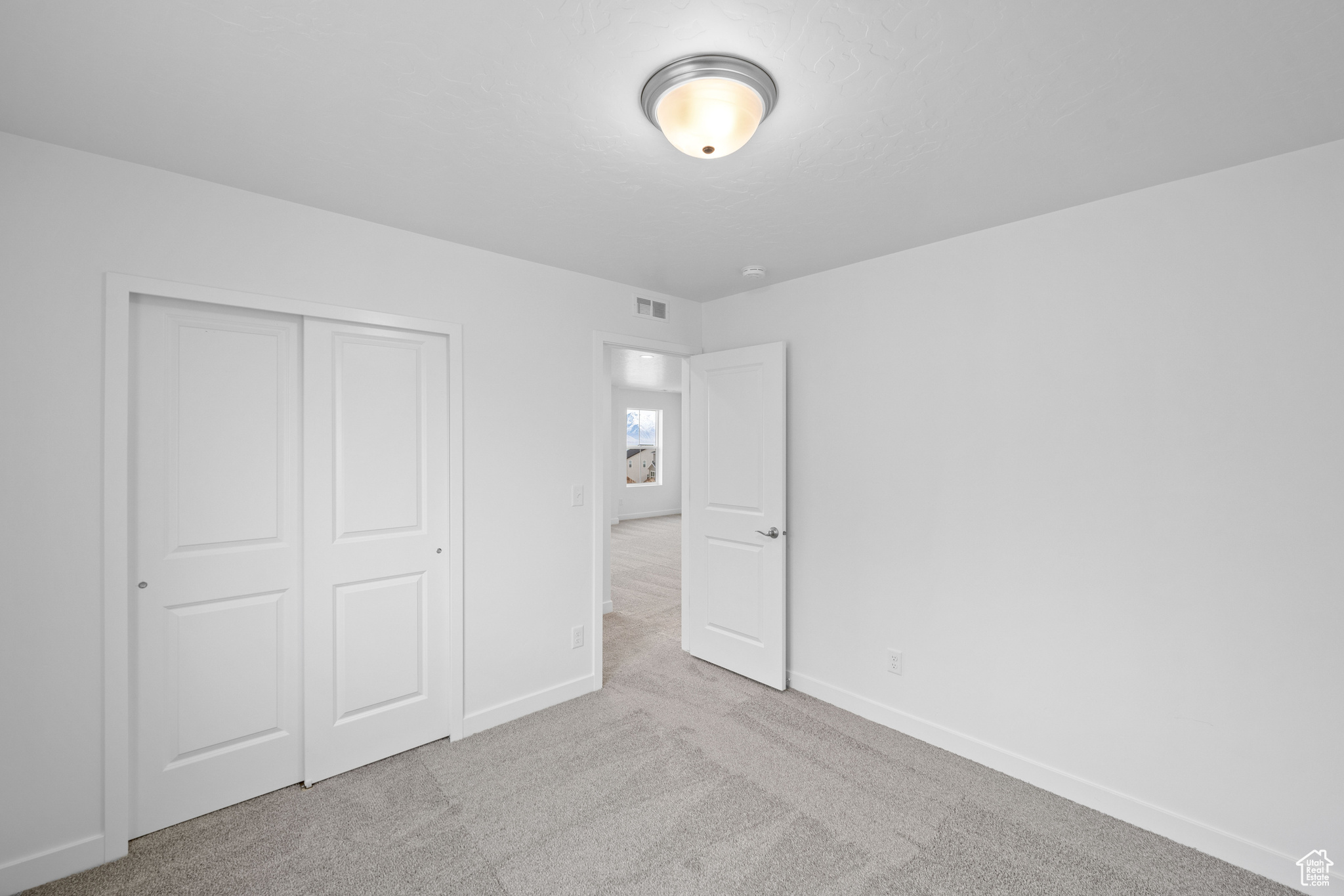 Unfurnished bedroom featuring light carpet and a closet