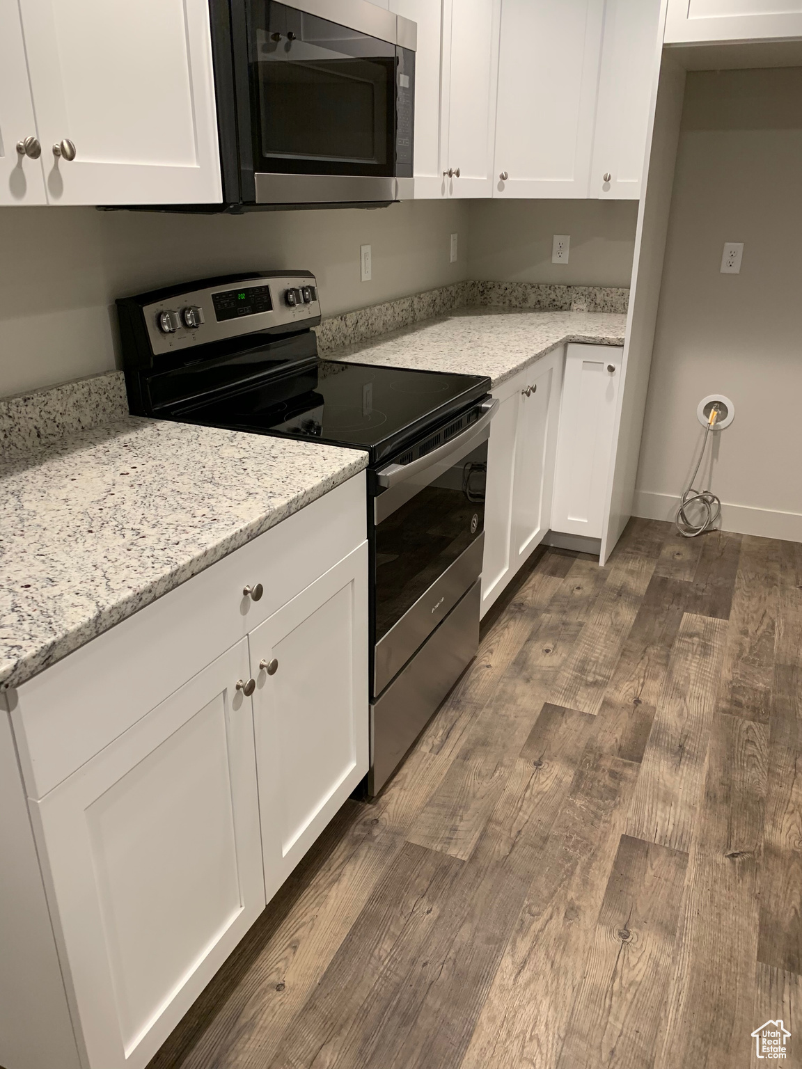 Kitchen featuring white cabinetry, light stone counters, dark hardwood / wood-style flooring, and appliances with stainless steel finishes