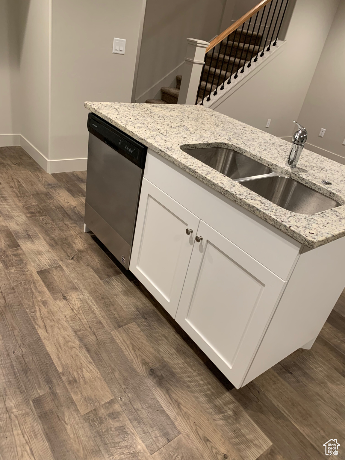 Kitchen featuring dishwasher, sink, white cabinets, dark hardwood / wood-style flooring, and light stone countertops