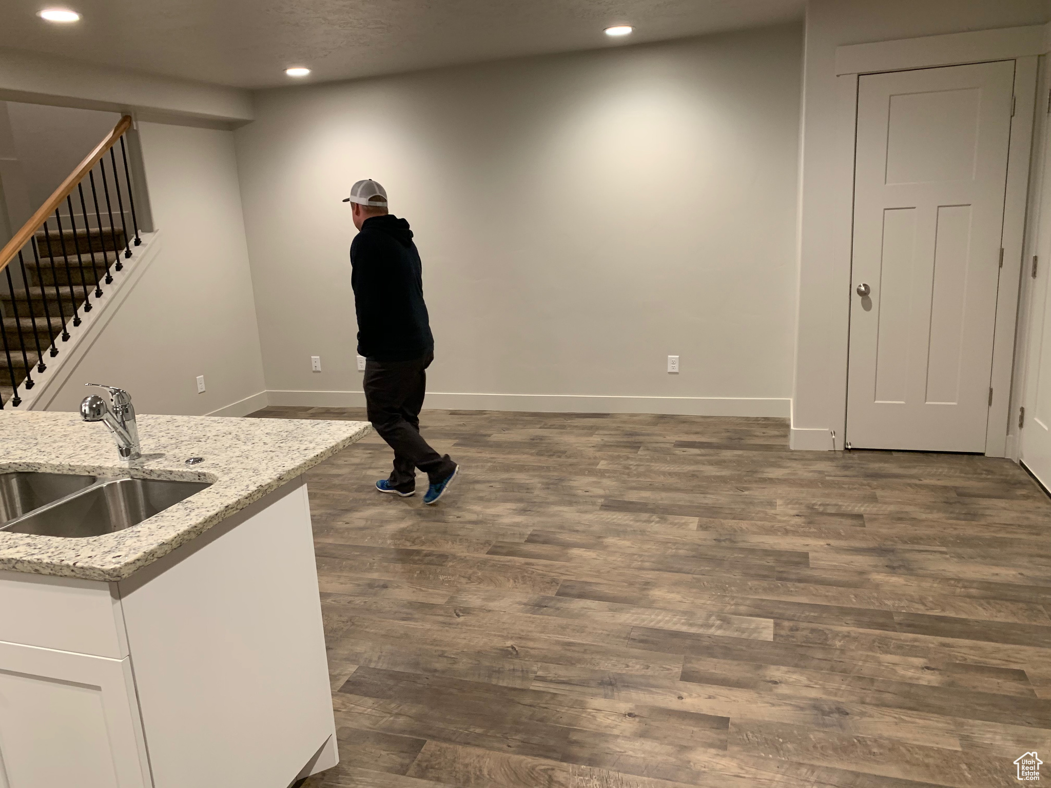 Interior space with white cabinetry, sink, light stone counters, and dark wood-type flooring