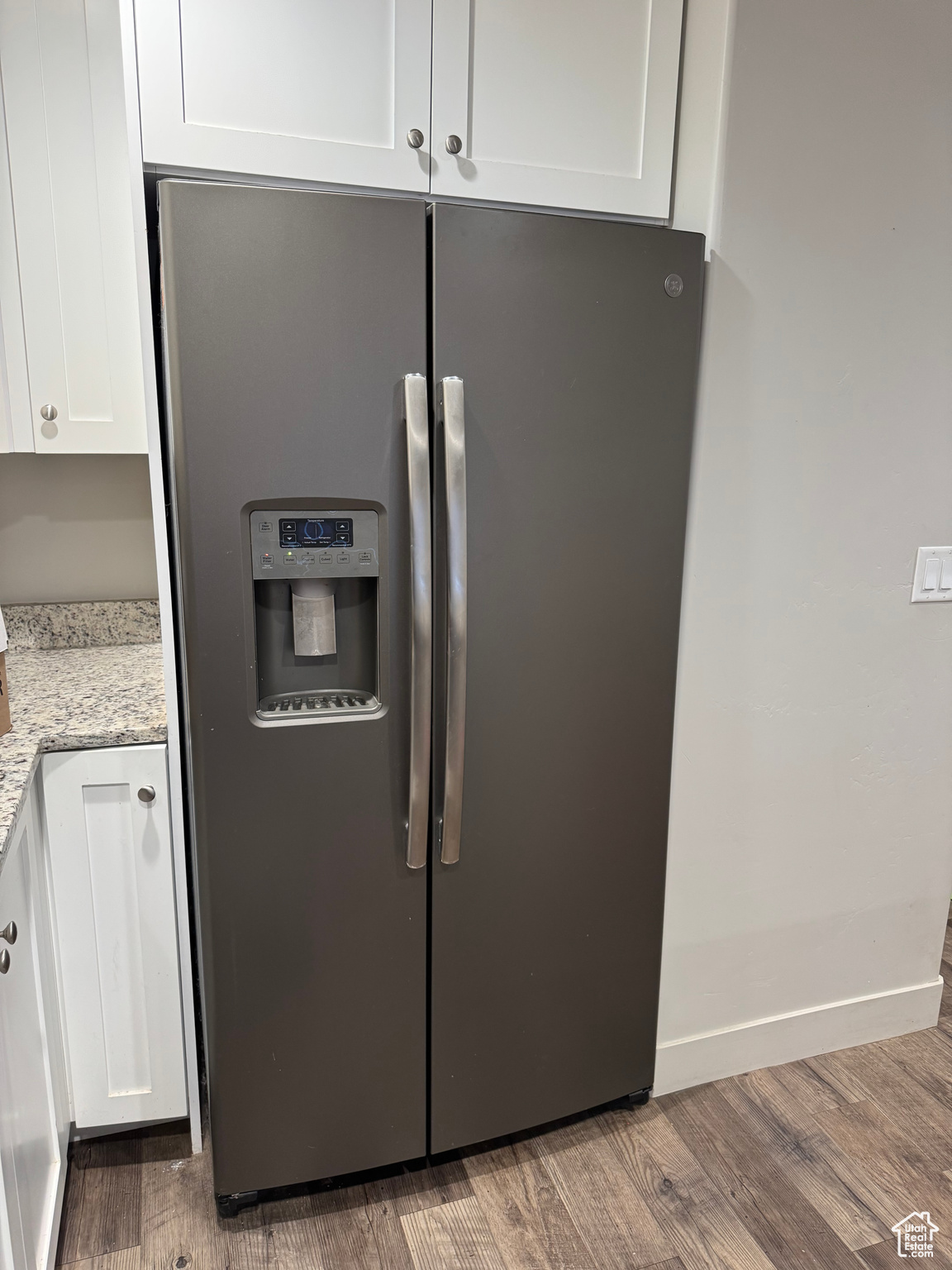 Room details with white cabinets, wood-type flooring, and stainless steel fridge