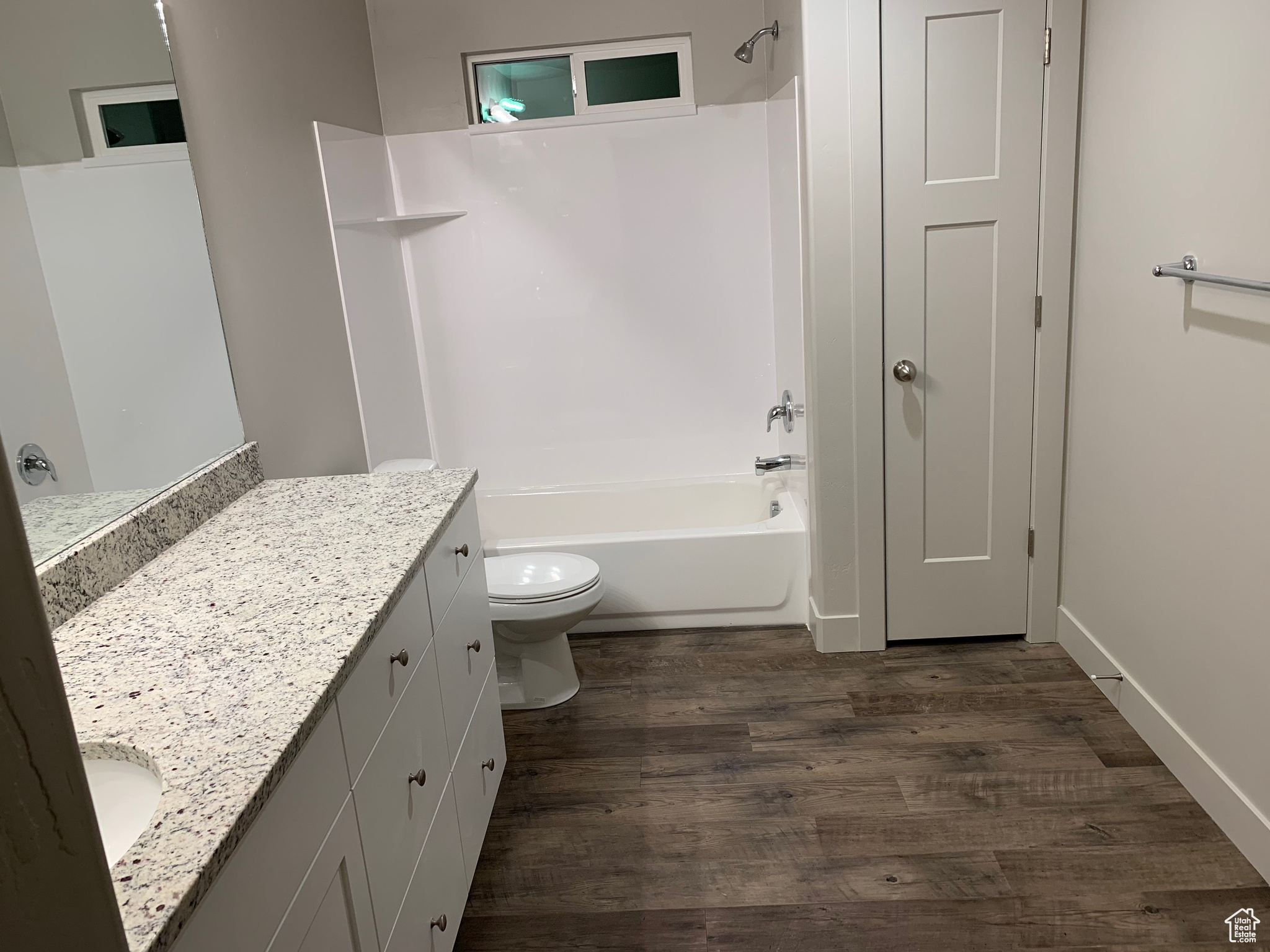 Full bathroom with vanity, hardwood / wood-style floors, shower / bathtub combination, and toilet