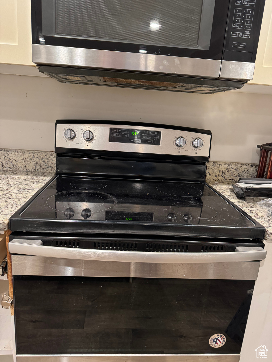 Kitchen featuring stainless steel appliances, white cabinetry, and light stone counters