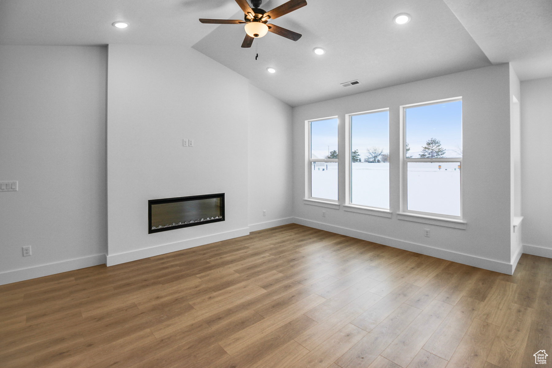 Open concept living room with ceiling fan and large windows