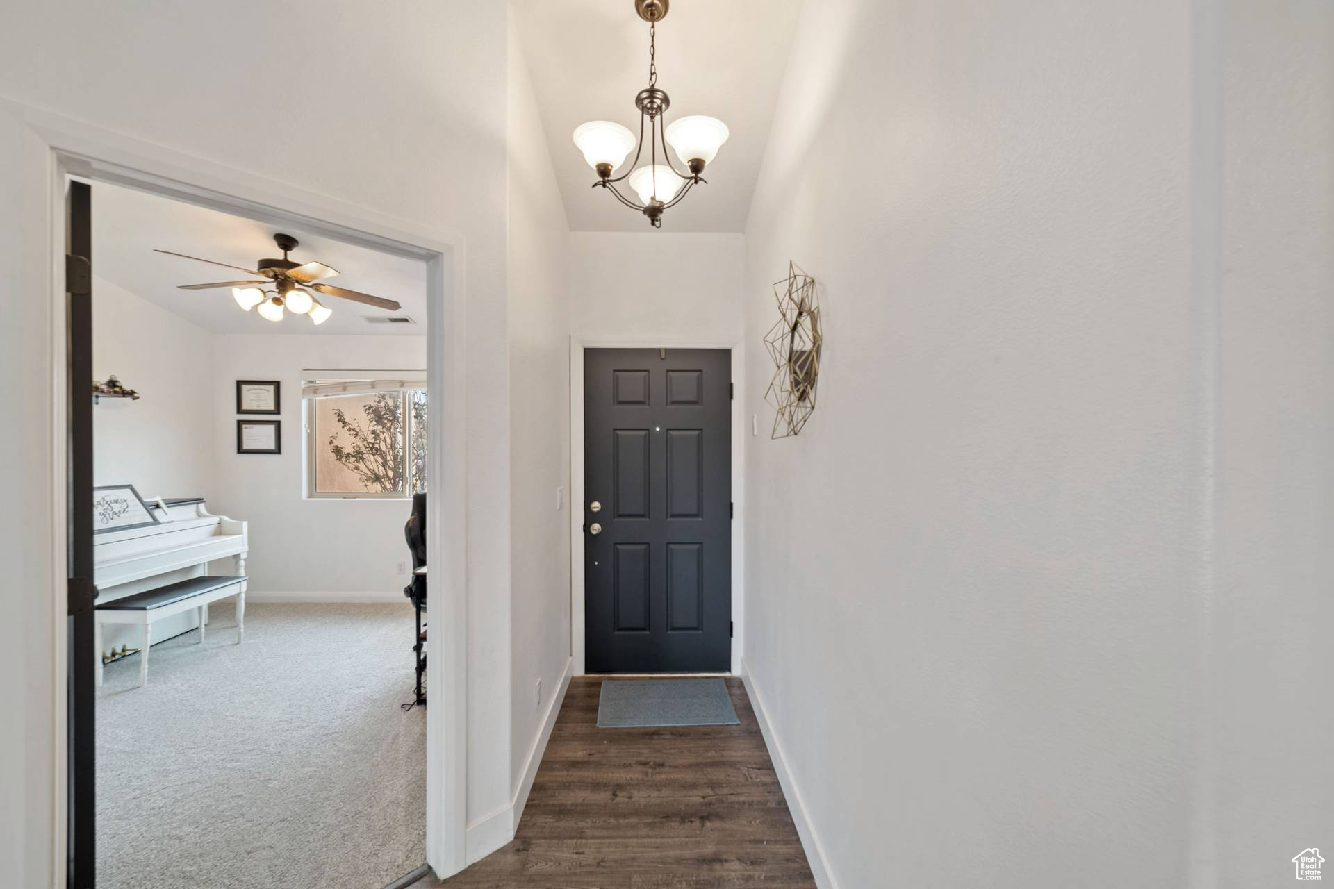 Carpeted entryway featuring ceiling fan with notable chandelier