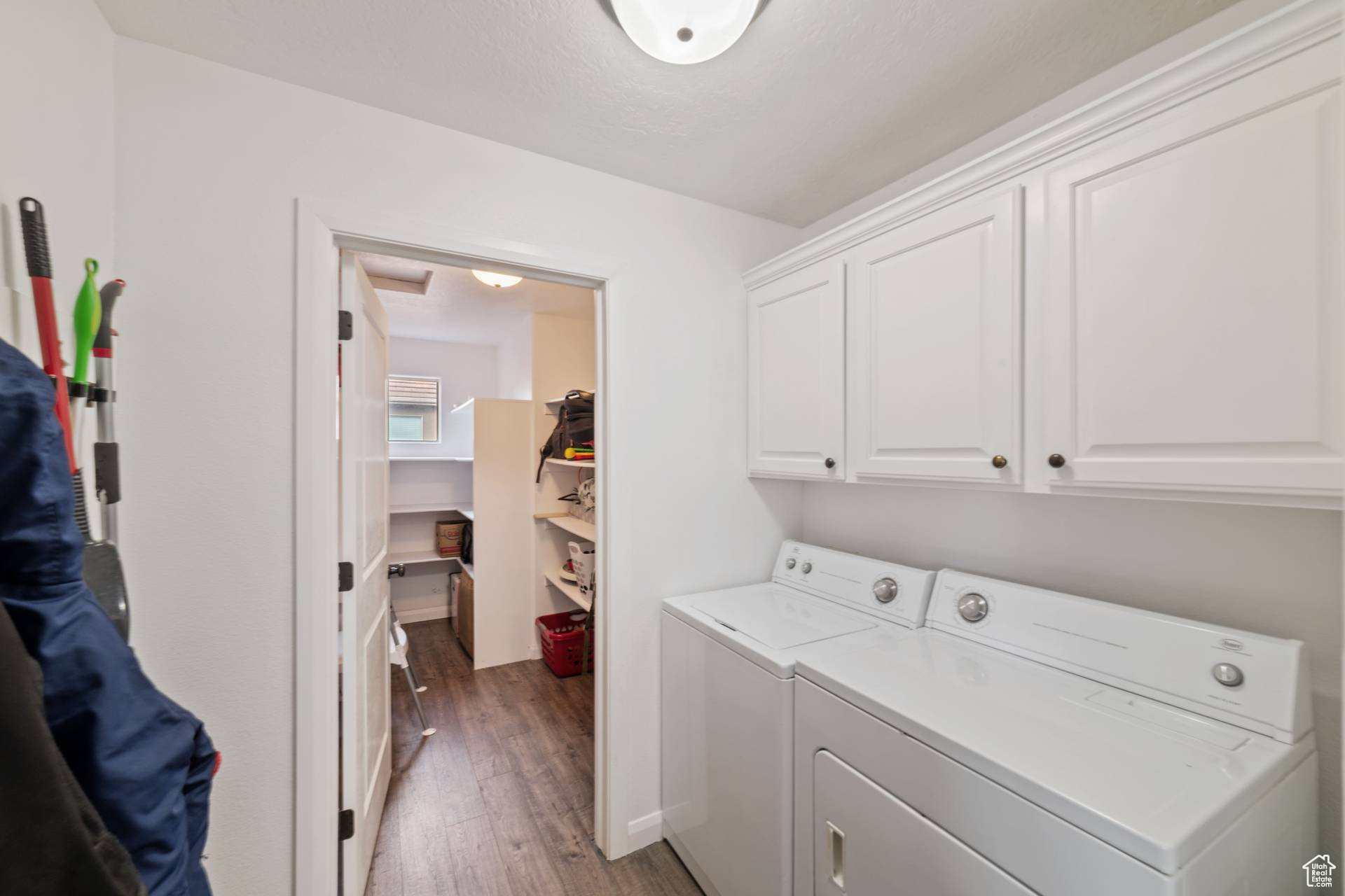 Clothes washing area with cabinets, washing machine and clothes dryer, and hardwood / wood-style flooring