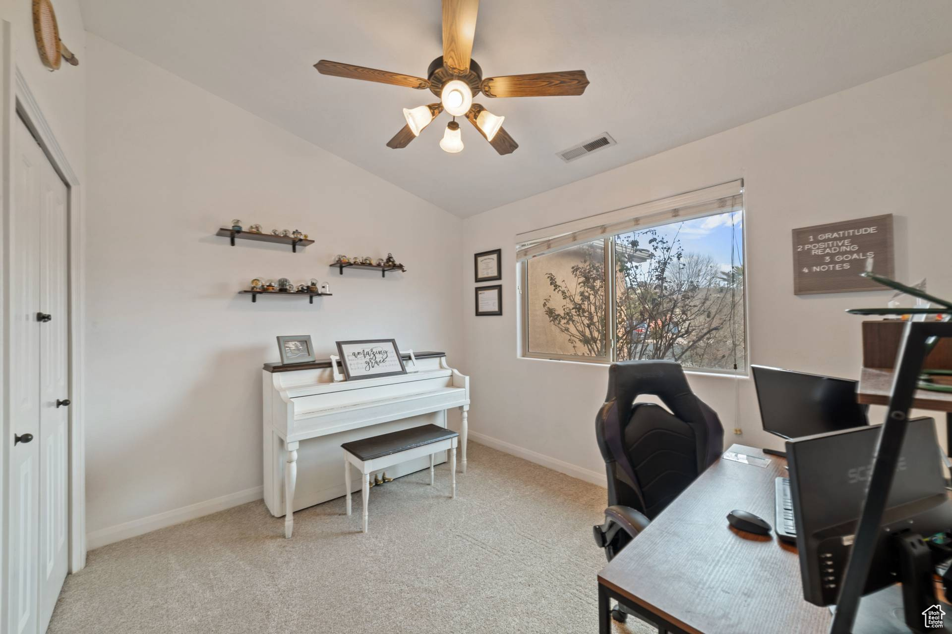 Office area featuring ceiling fan, lofted ceiling, and light carpet