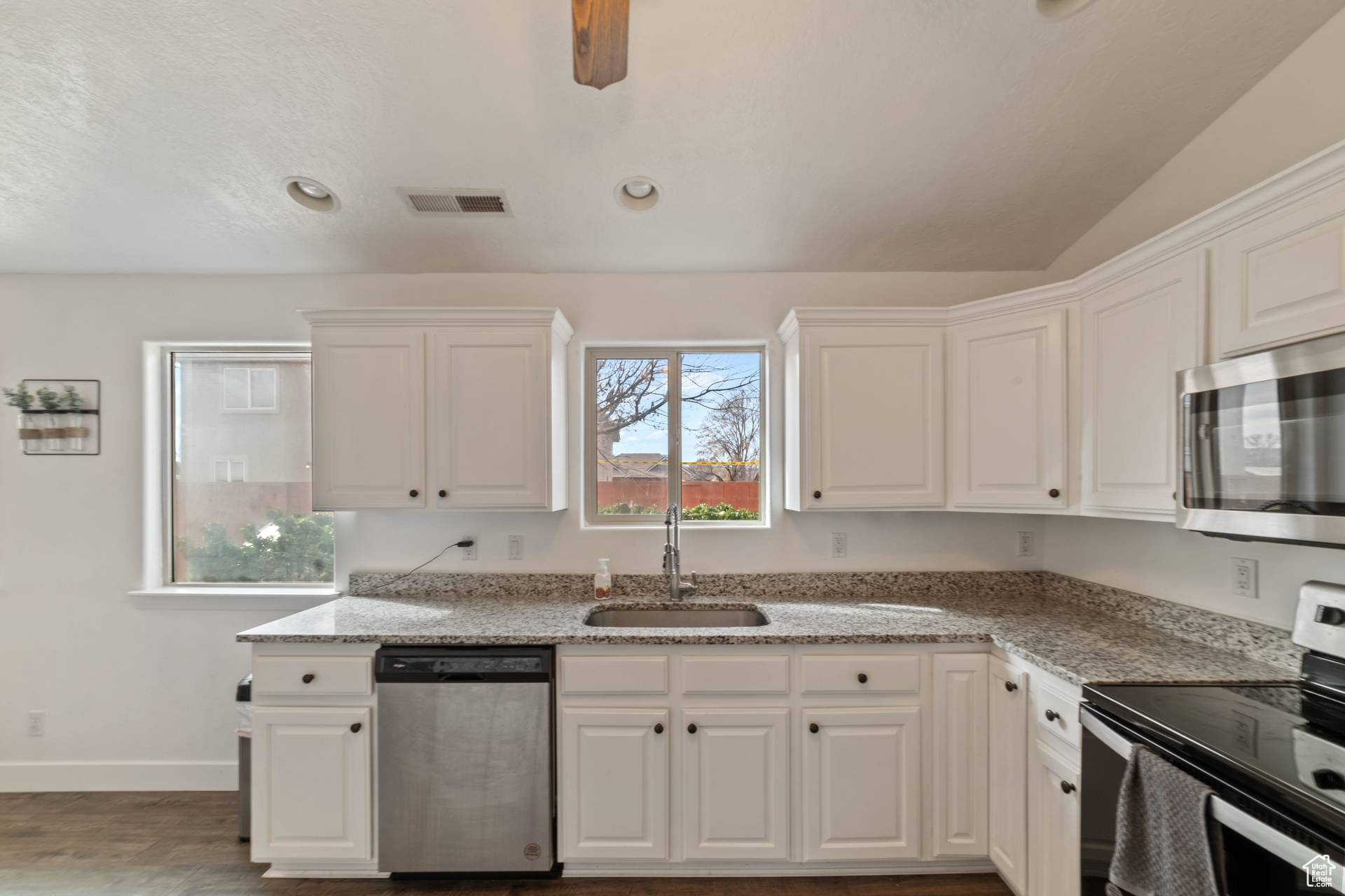 Kitchen featuring white cabinetry, appliances with stainless steel finishes, sink, and light stone counters