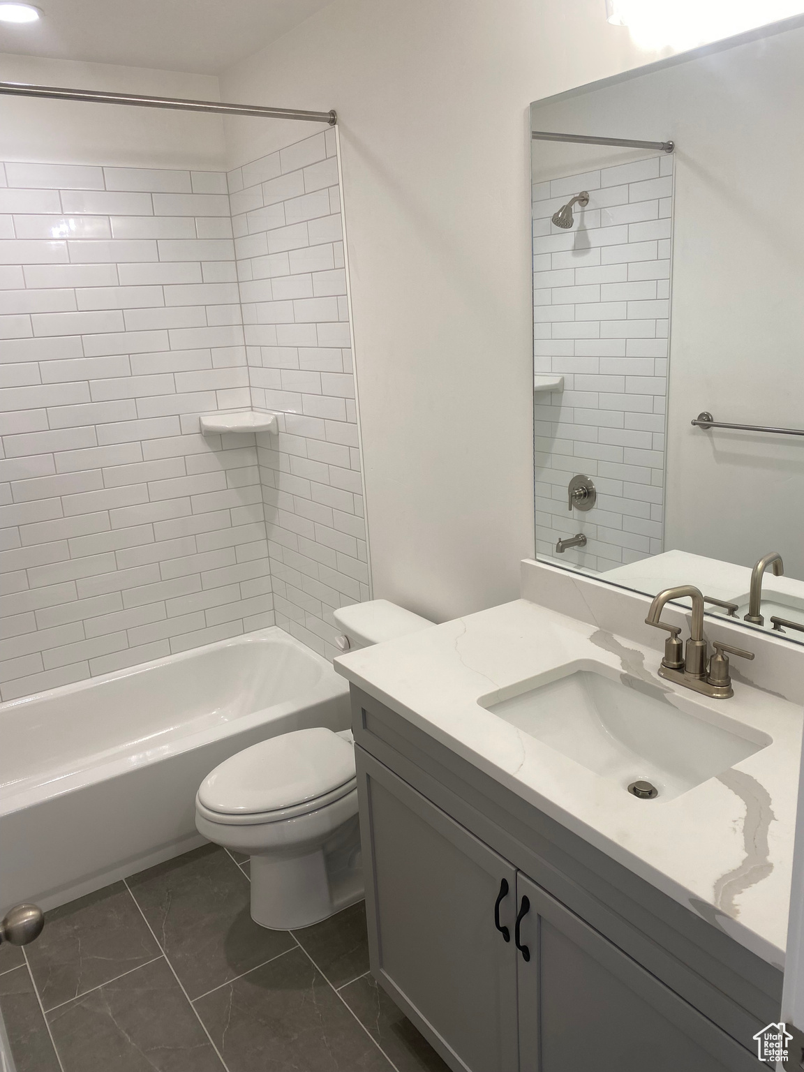 Full bathroom featuring tiled shower / bath, vanity, and toilet