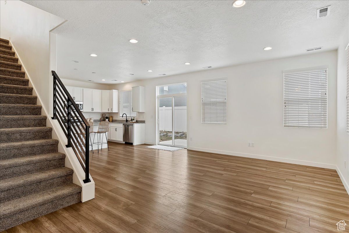 Unfurnished living room featuring sink, light hardwood / wood-style flooring, and a textured ceiling