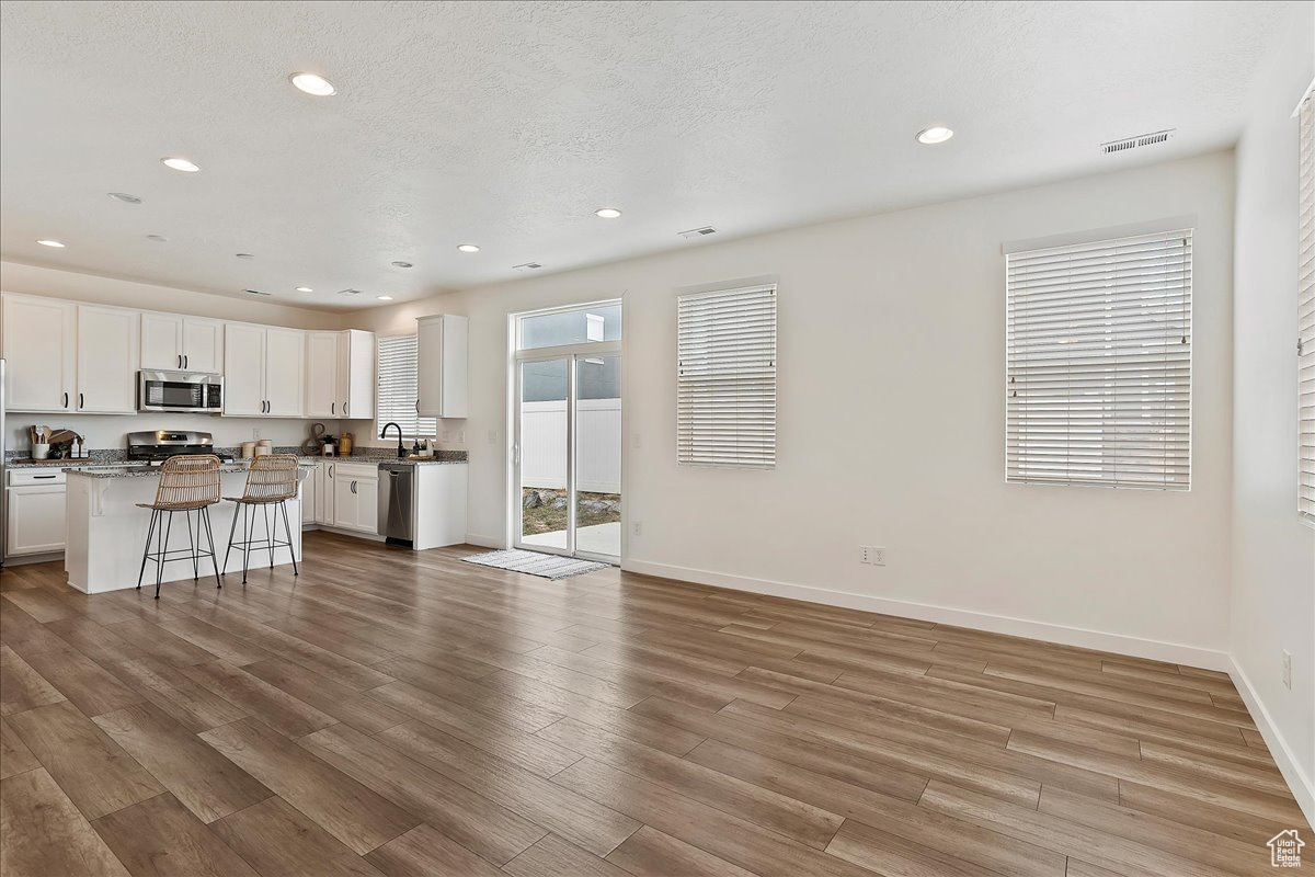 Kitchen with a kitchen bar, a center island, appliances with stainless steel finishes, light hardwood / wood-style floors, and white cabinets