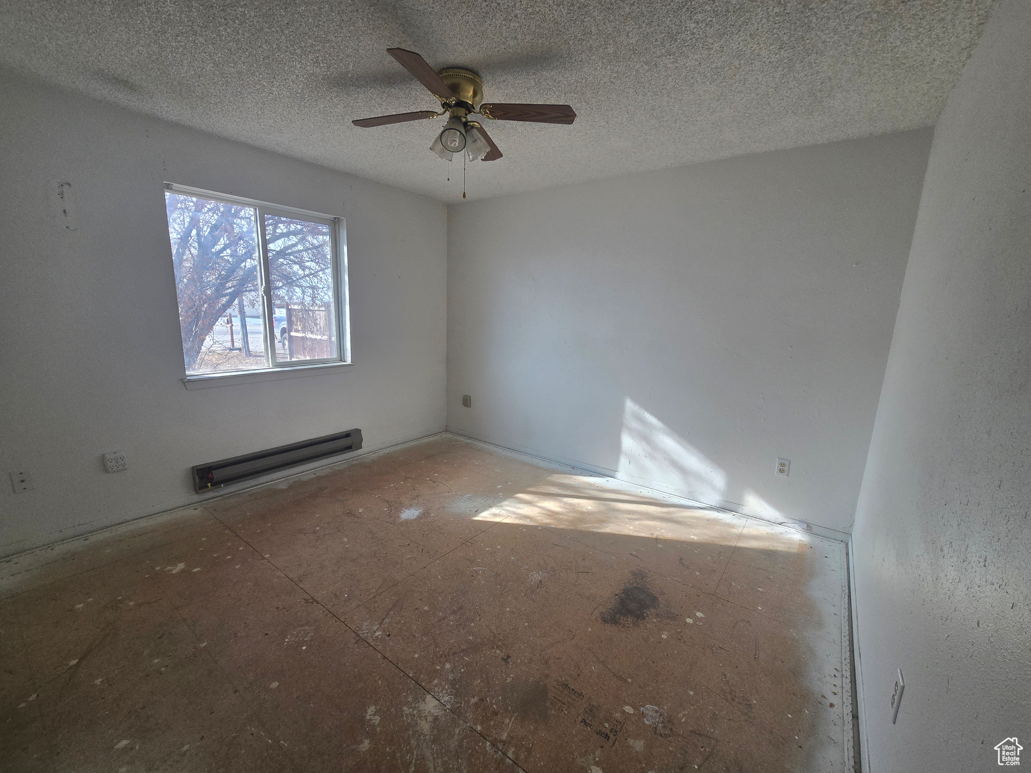 Unfurnished room featuring ceiling fan, a textured ceiling, and a baseboard heating unit