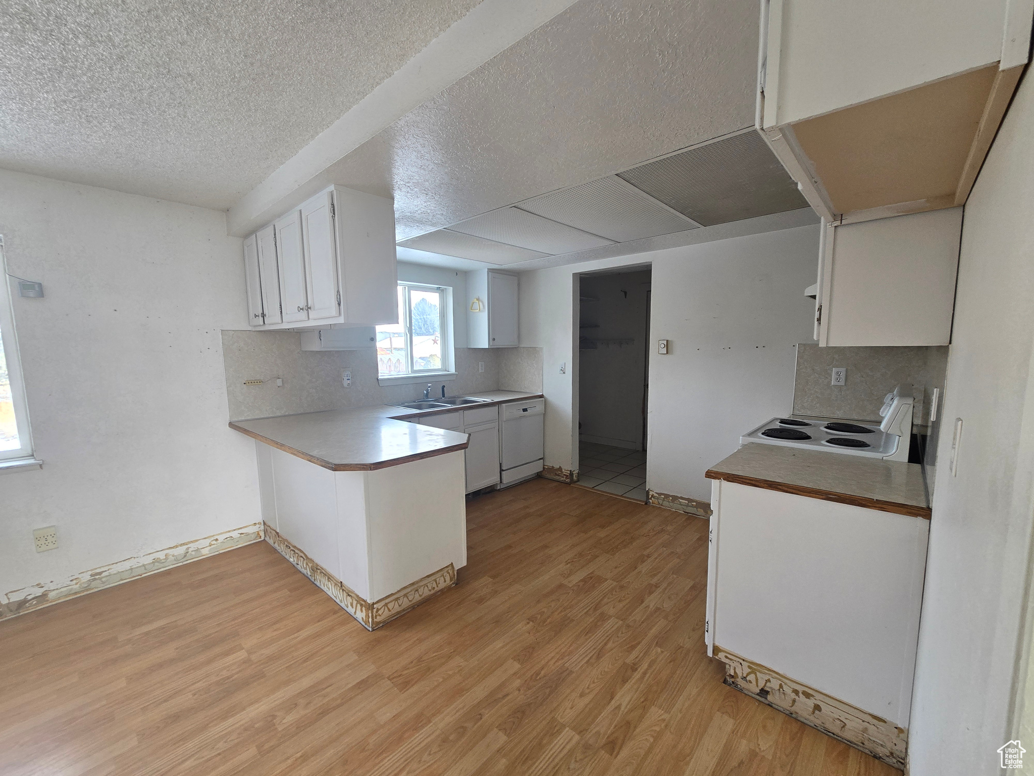 Kitchen featuring sink, white cabinetry, tasteful backsplash, light hardwood / wood-style flooring, and a textured ceiling