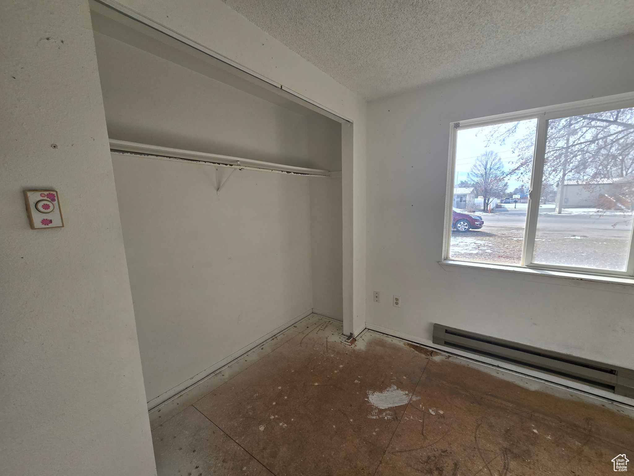 Unfurnished bedroom with a baseboard radiator, a closet, and a textured ceiling