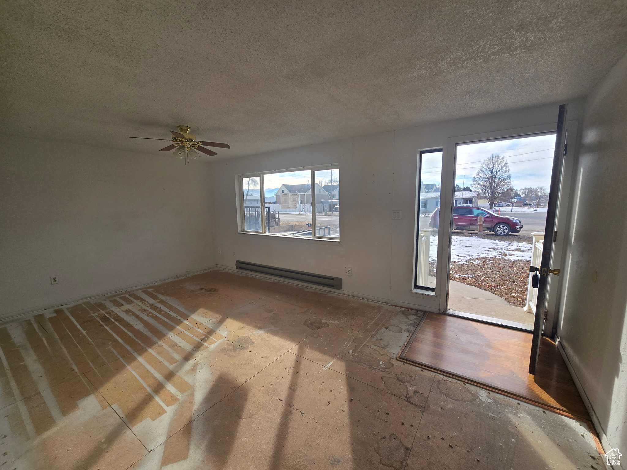 Entrance foyer featuring a baseboard heating unit, a textured ceiling, and ceiling fan