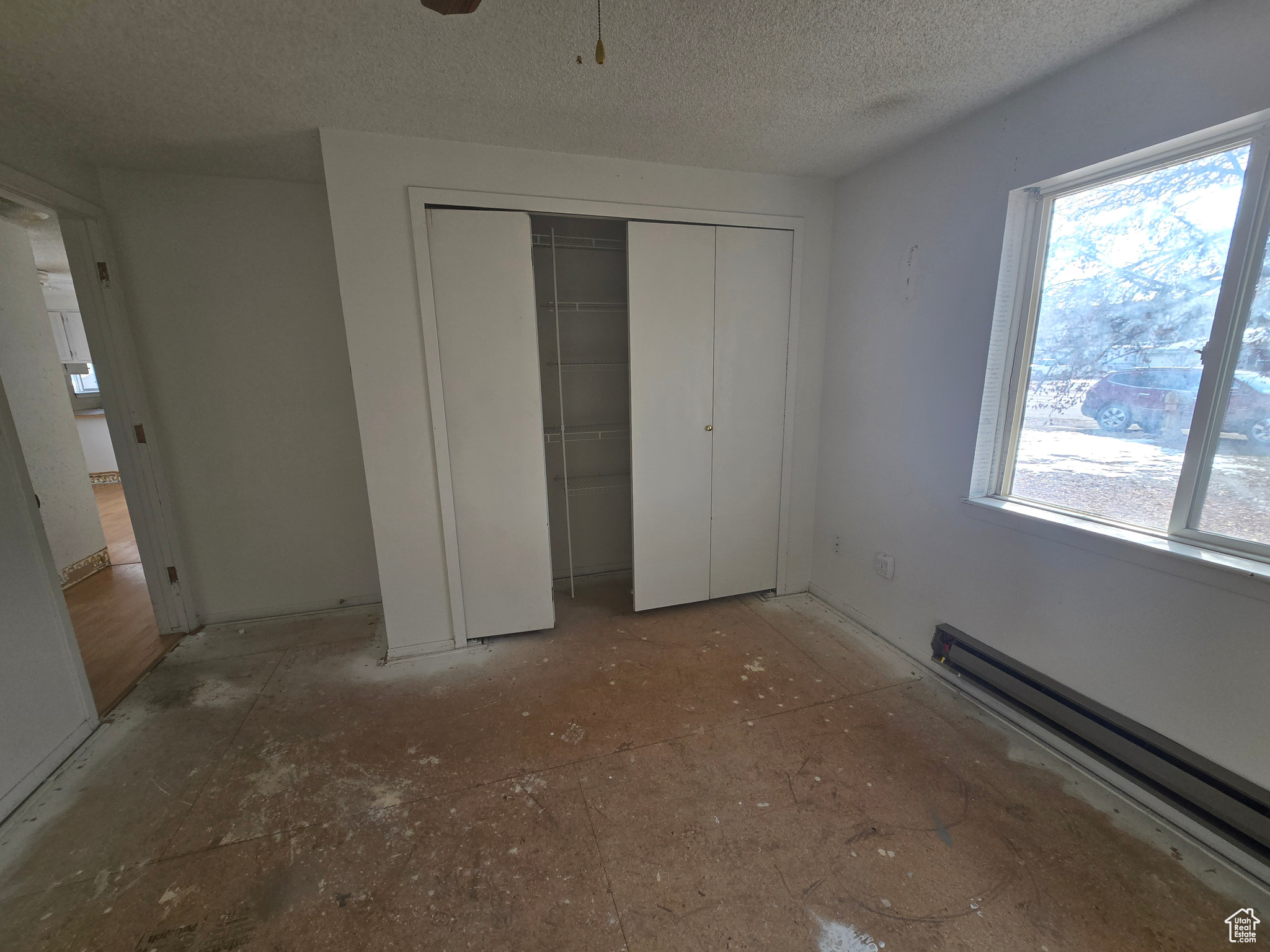 Unfurnished bedroom with a baseboard radiator, a closet, and a textured ceiling