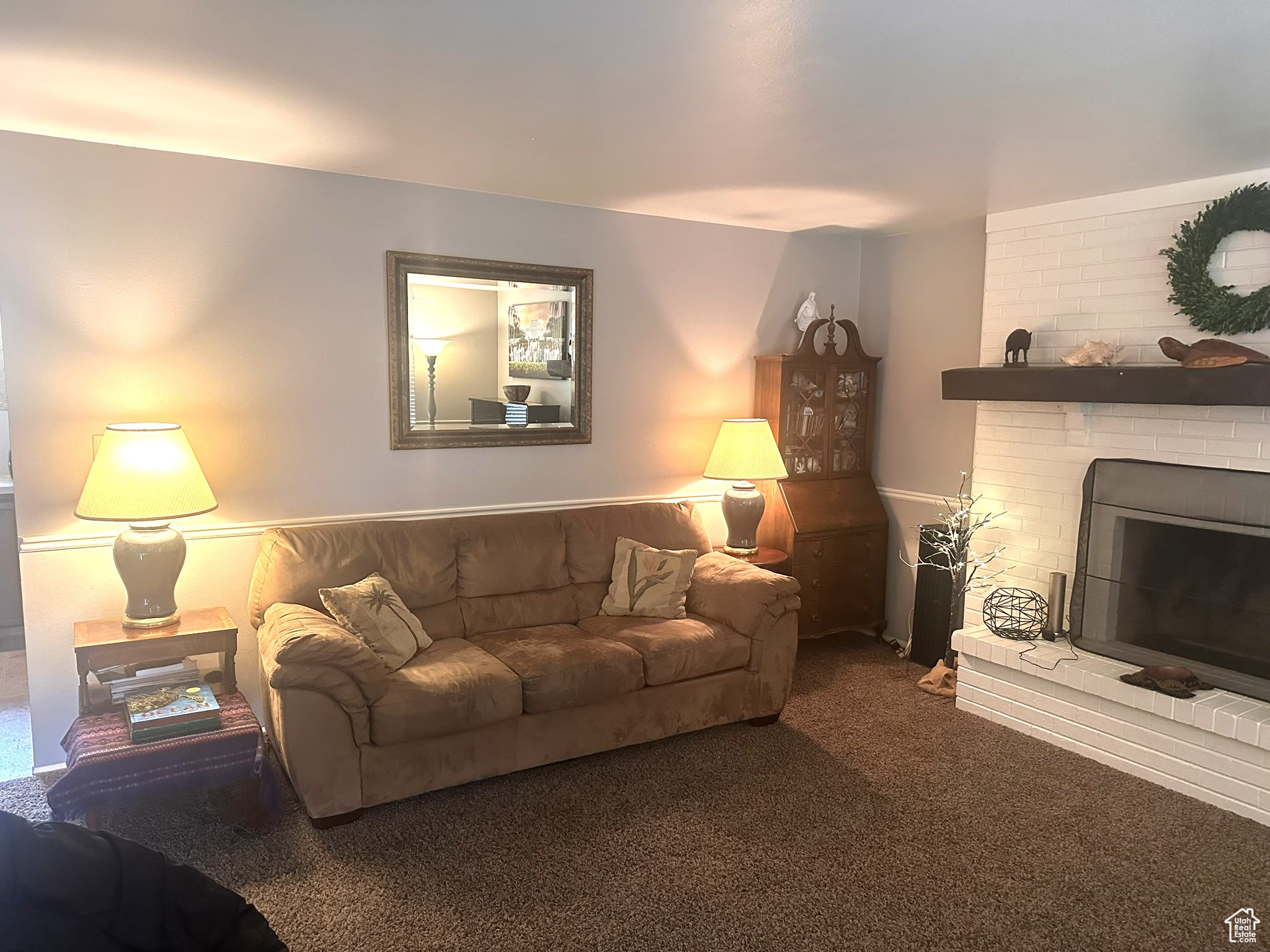 Living room with a brick fireplace and dark colored carpet