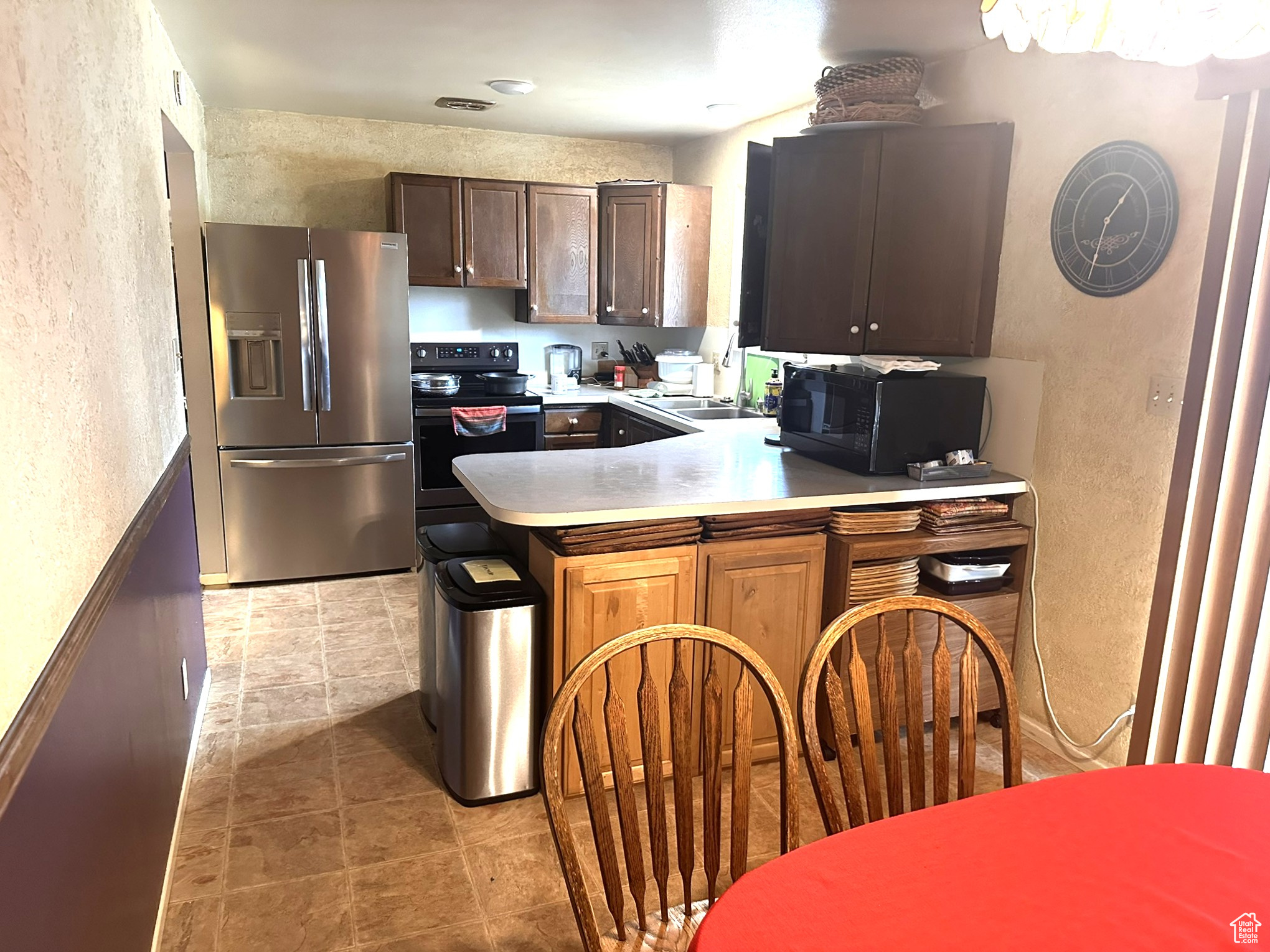 Kitchen with stainless steel fridge with ice dispenser, electric range oven, sink, and kitchen peninsula